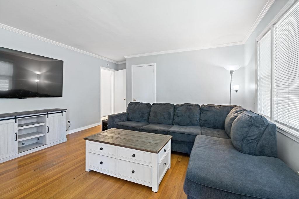 Living room with light wood-type flooring and crown molding