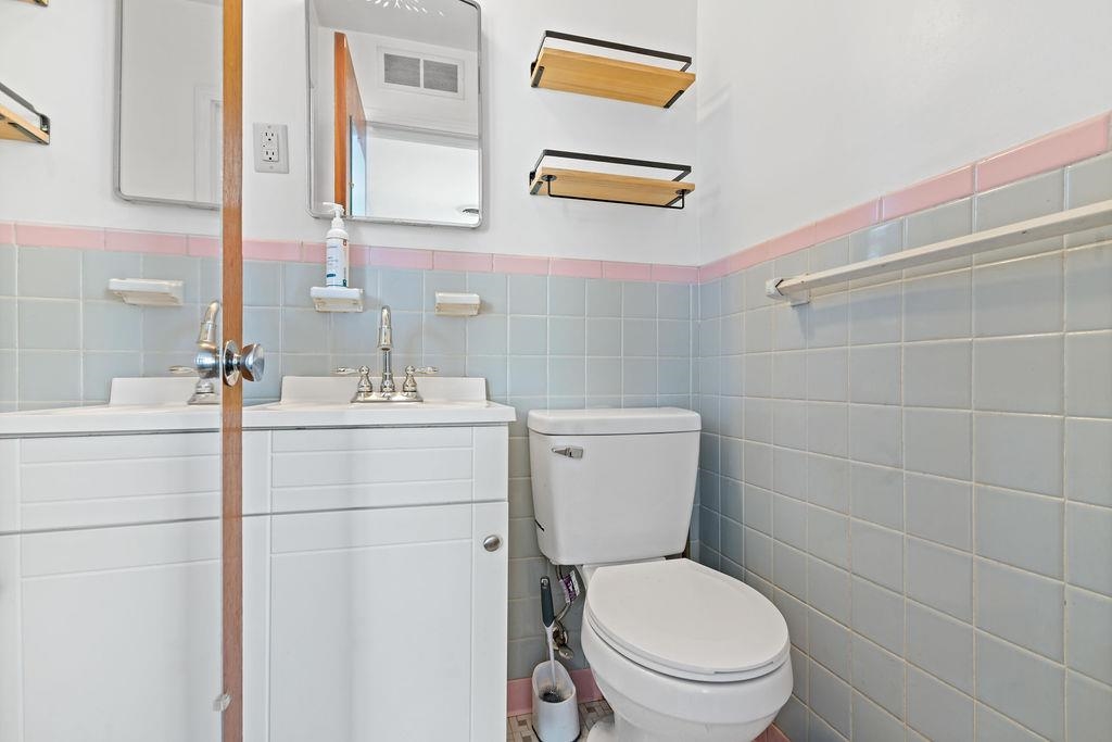 Bathroom featuring vanity, tile walls, and toilet
