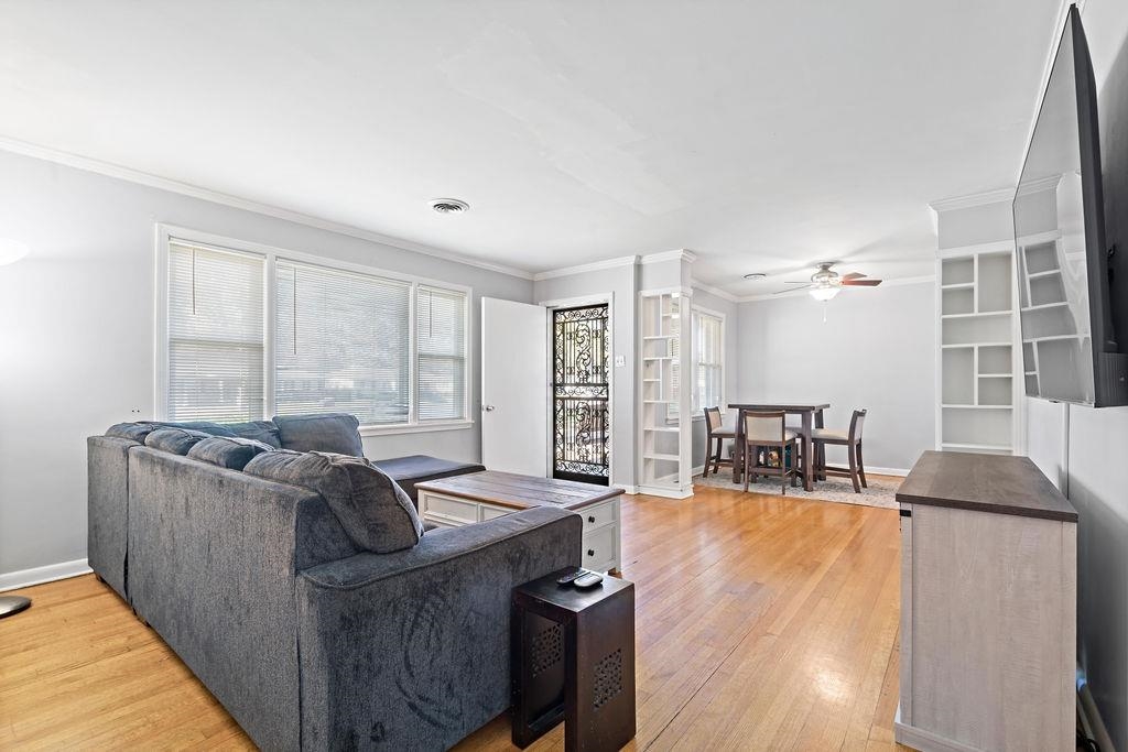 Living room featuring hardwood / wood-style floors, ceiling fan, and crown molding