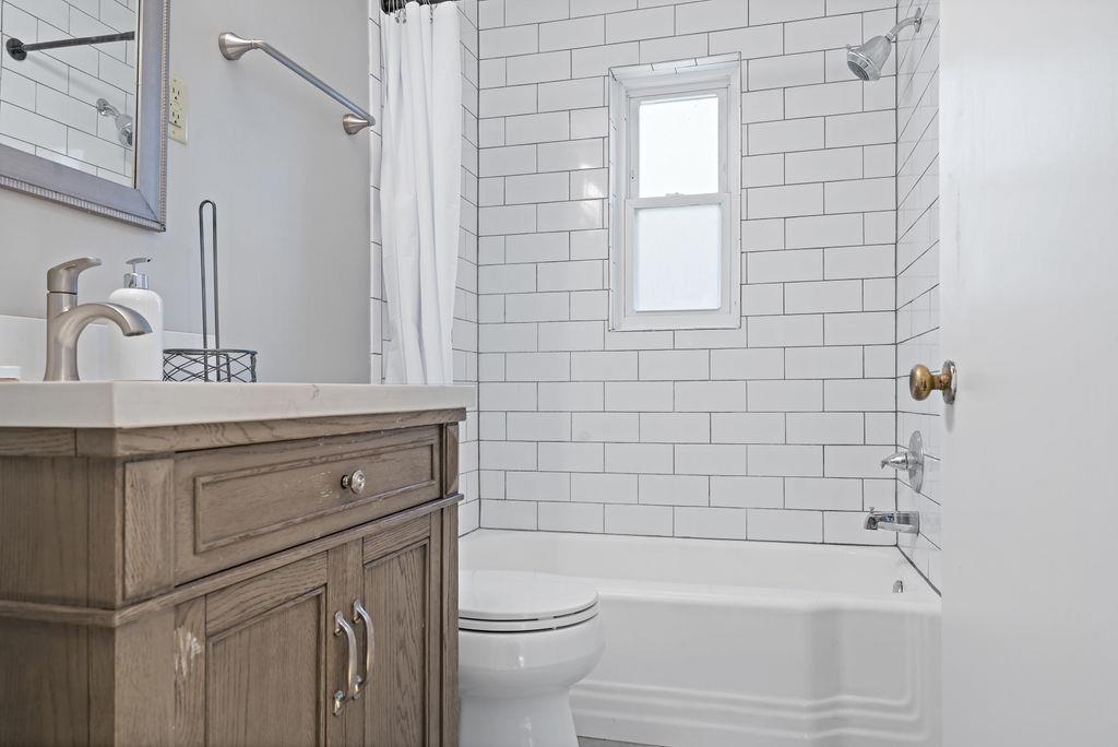 Full bathroom with vanity, shower / bathtub combination with curtain, and toilet