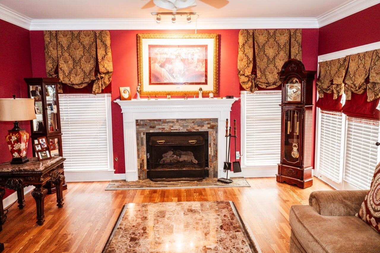 Living room with a stone fireplace, wood-type flooring, and ornamental molding