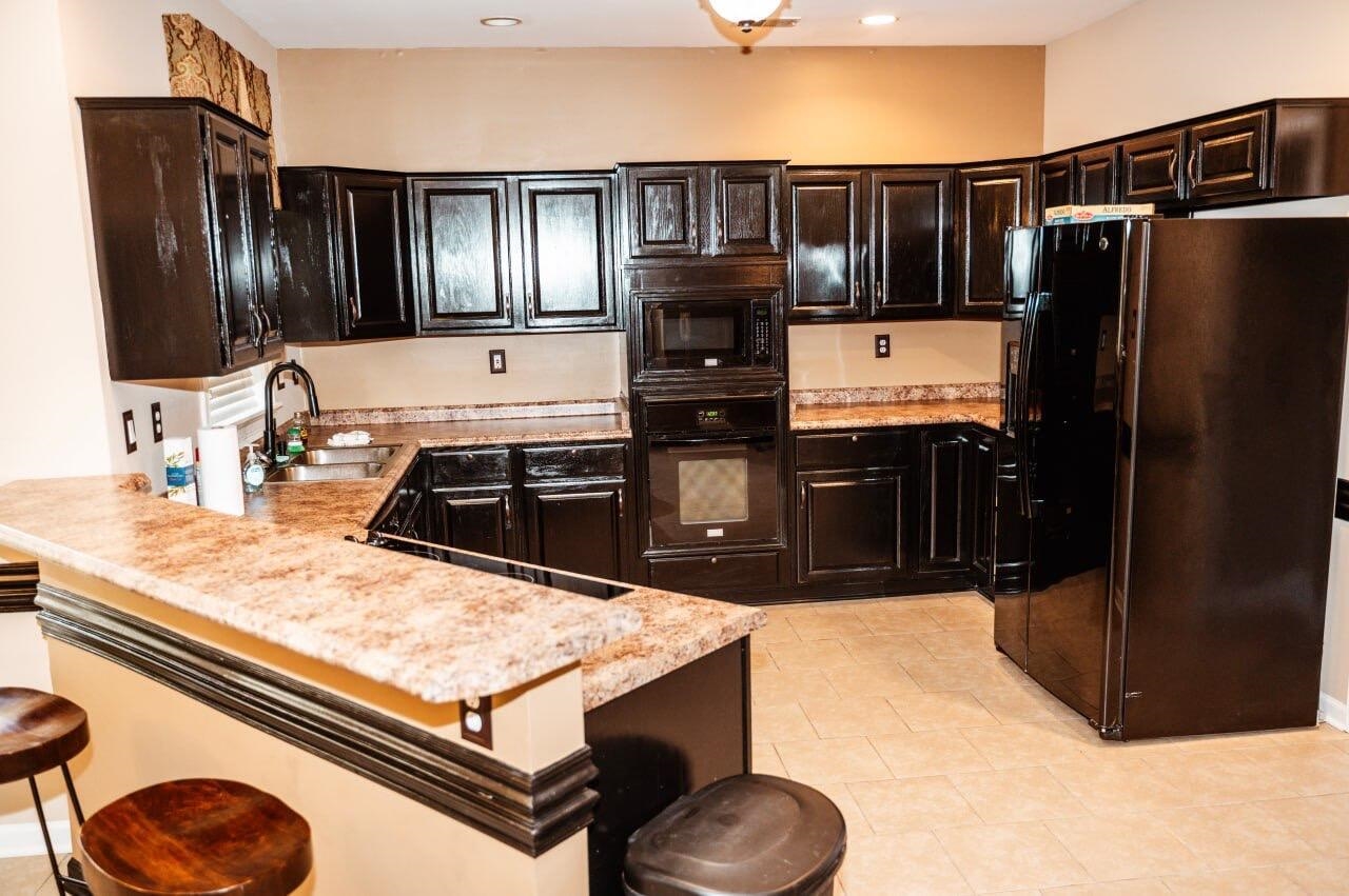 Kitchen featuring light stone countertops, sink, kitchen peninsula, a breakfast bar, and black appliances