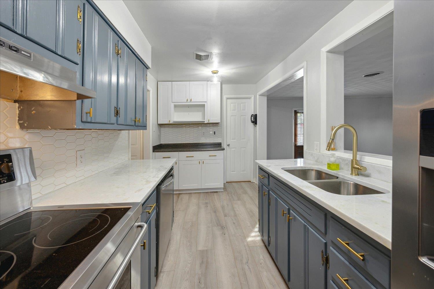 Kitchen with sink, blue cabinets, light hardwood / wood-style floors, white cabinets, and appliances with stainless steel finishes