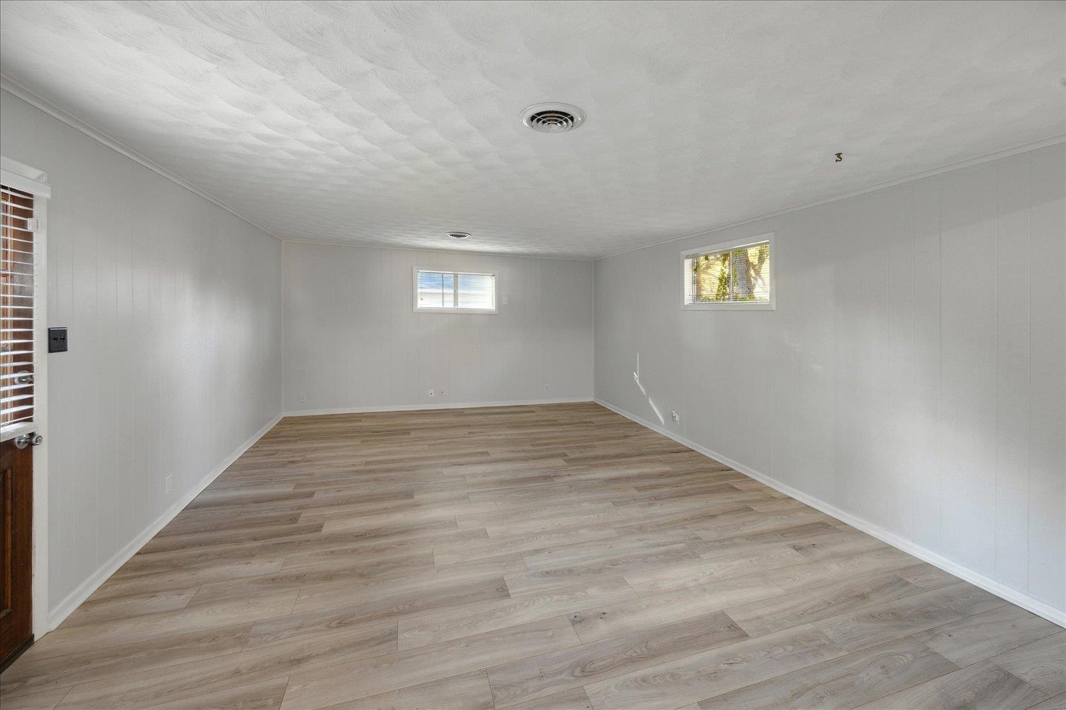Basement with a textured ceiling, light hardwood / wood-style floors, and a wealth of natural light