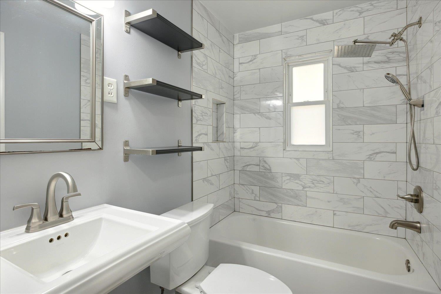 Full bathroom featuring tiled shower / bath combo, toilet, and sink