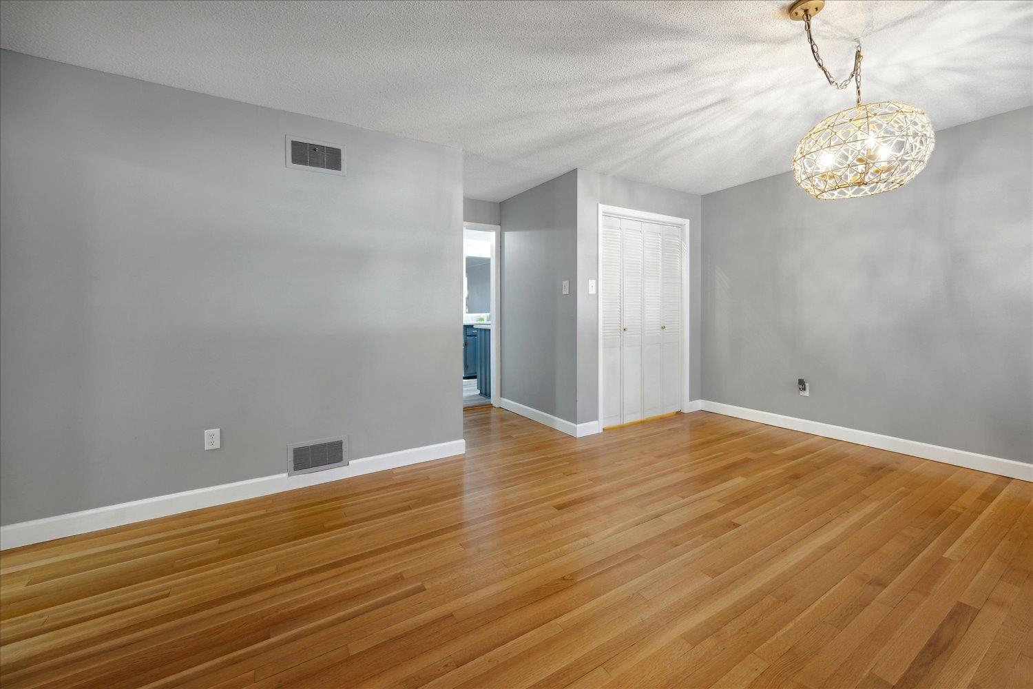 Empty room with hardwood / wood-style floors, a textured ceiling, and an inviting chandelier