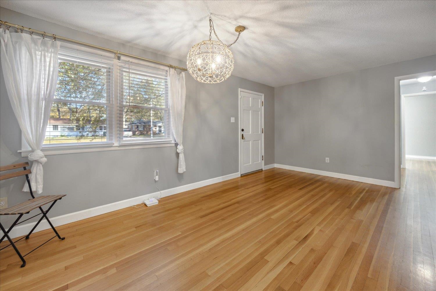 Empty room with a chandelier, a textured ceiling, and hardwood / wood-style flooring