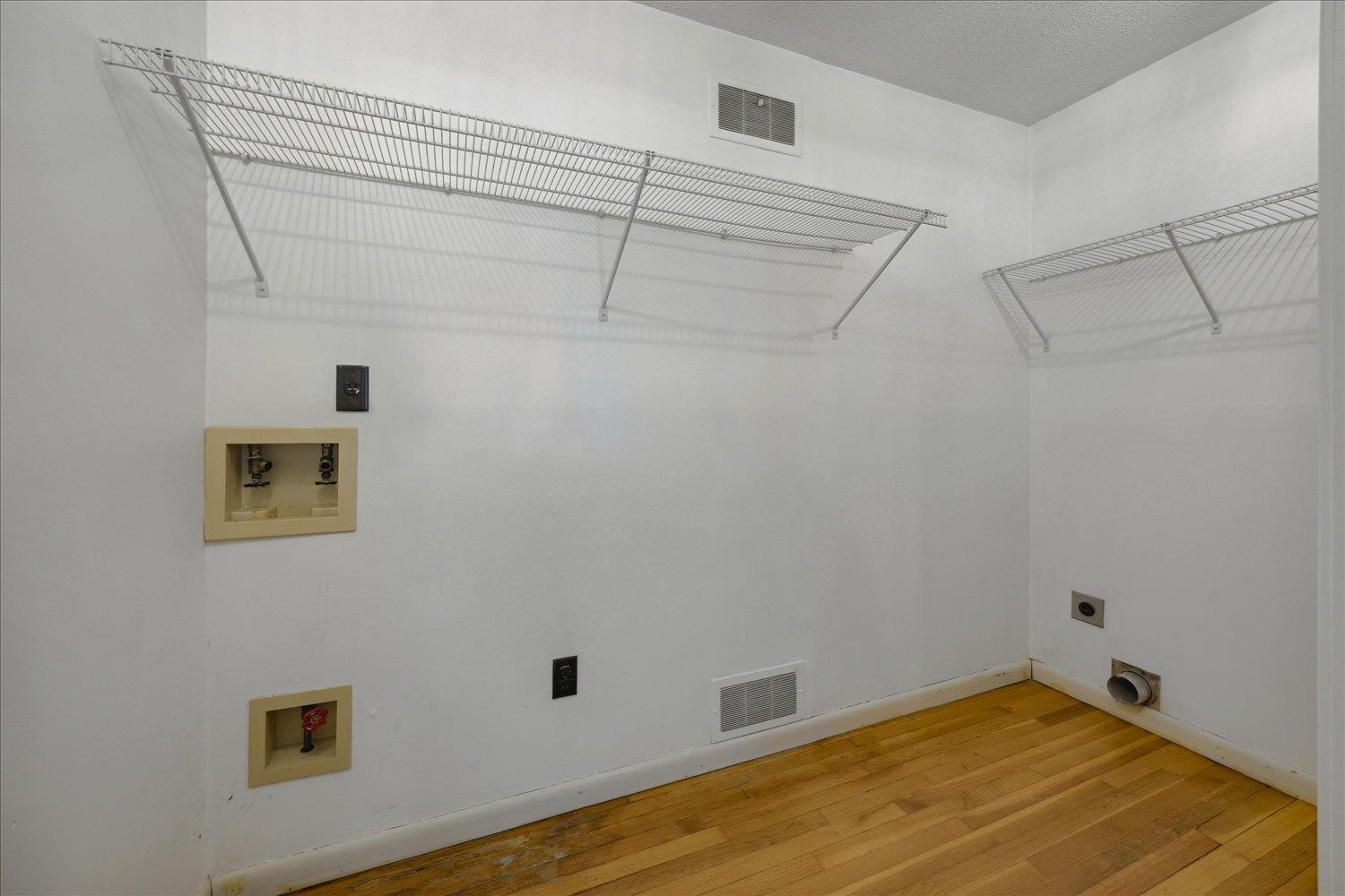 Laundry area with hardwood / wood-style flooring, electric dryer hookup, a textured ceiling, and hookup for a washing machine