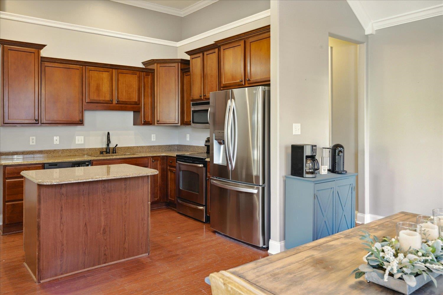 Kitchen featuring crown molding, sink, hardwood / wood-style flooring, appliances with stainless steel finishes, and light stone counters