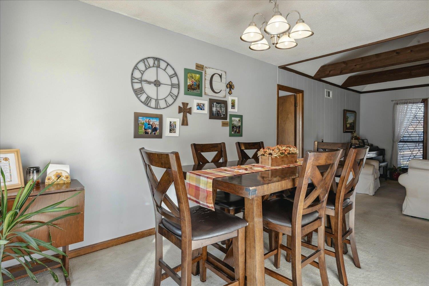 Dining area with beam ceiling, light colored carpet, a textured ceiling, and an inviting chandelier