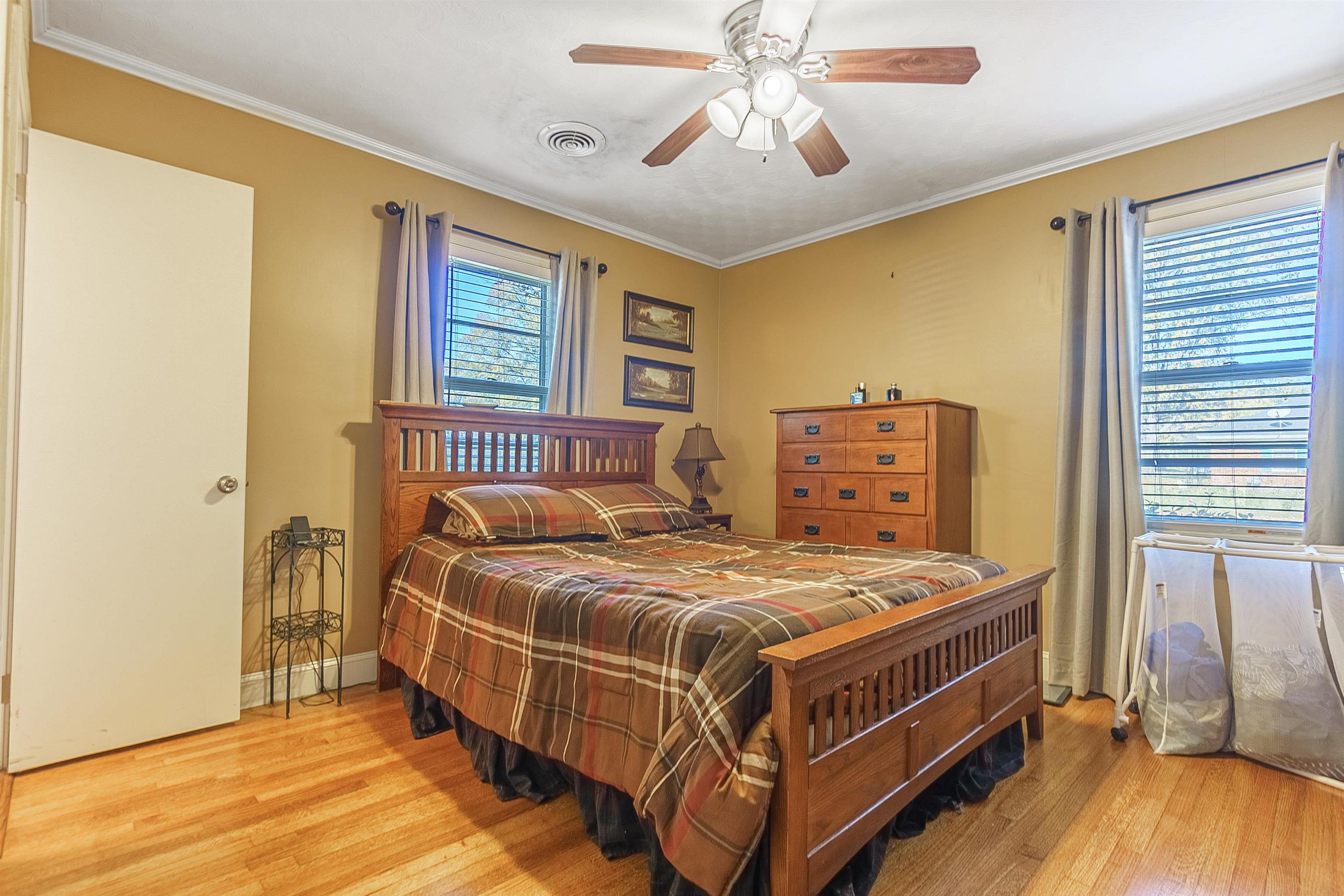 Bedroom featuring multiple windows, ceiling fan, and light hardwood / wood-style flooring