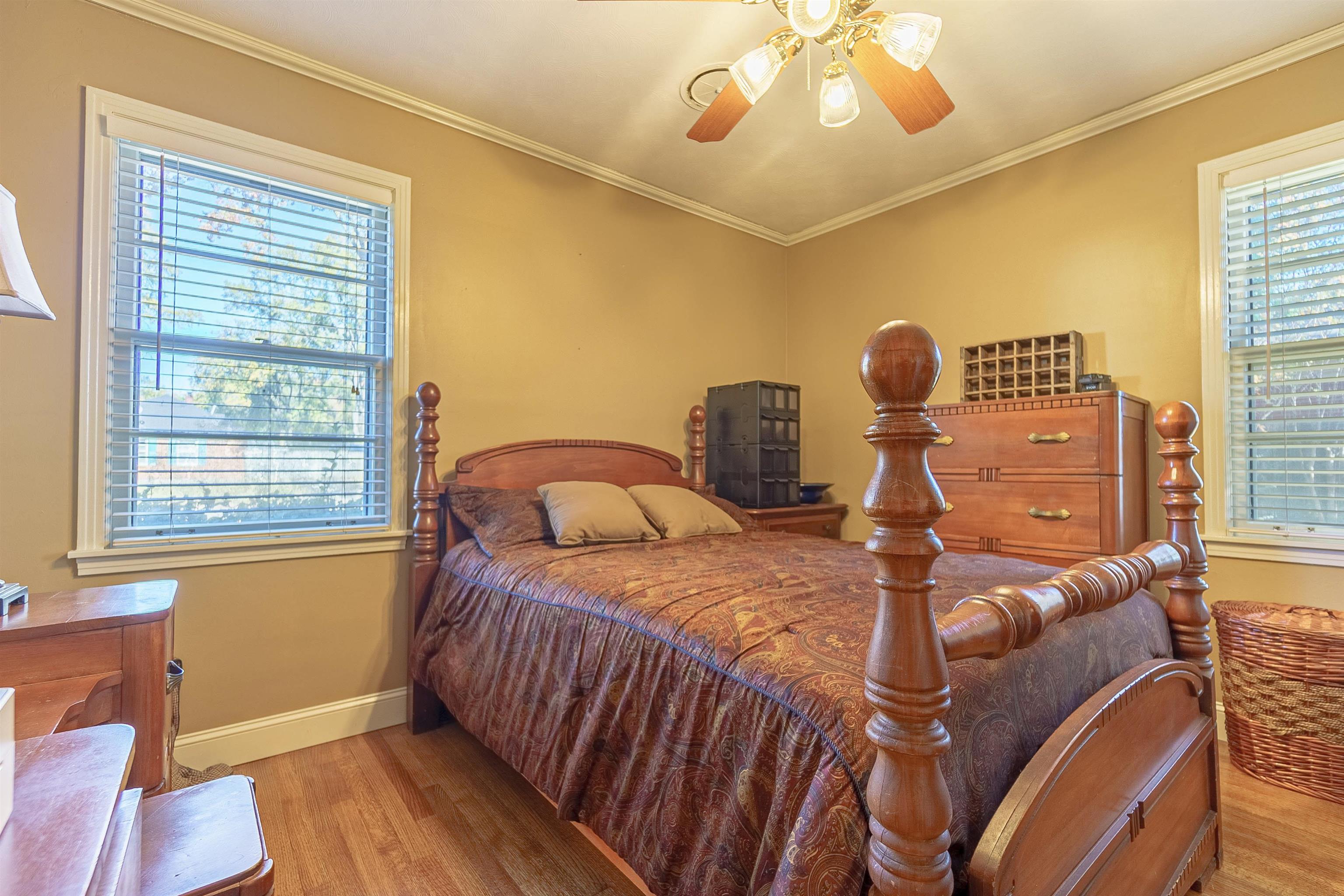 Bedroom featuring light wood-type flooring, multiple windows, crown molding, and ceiling fan