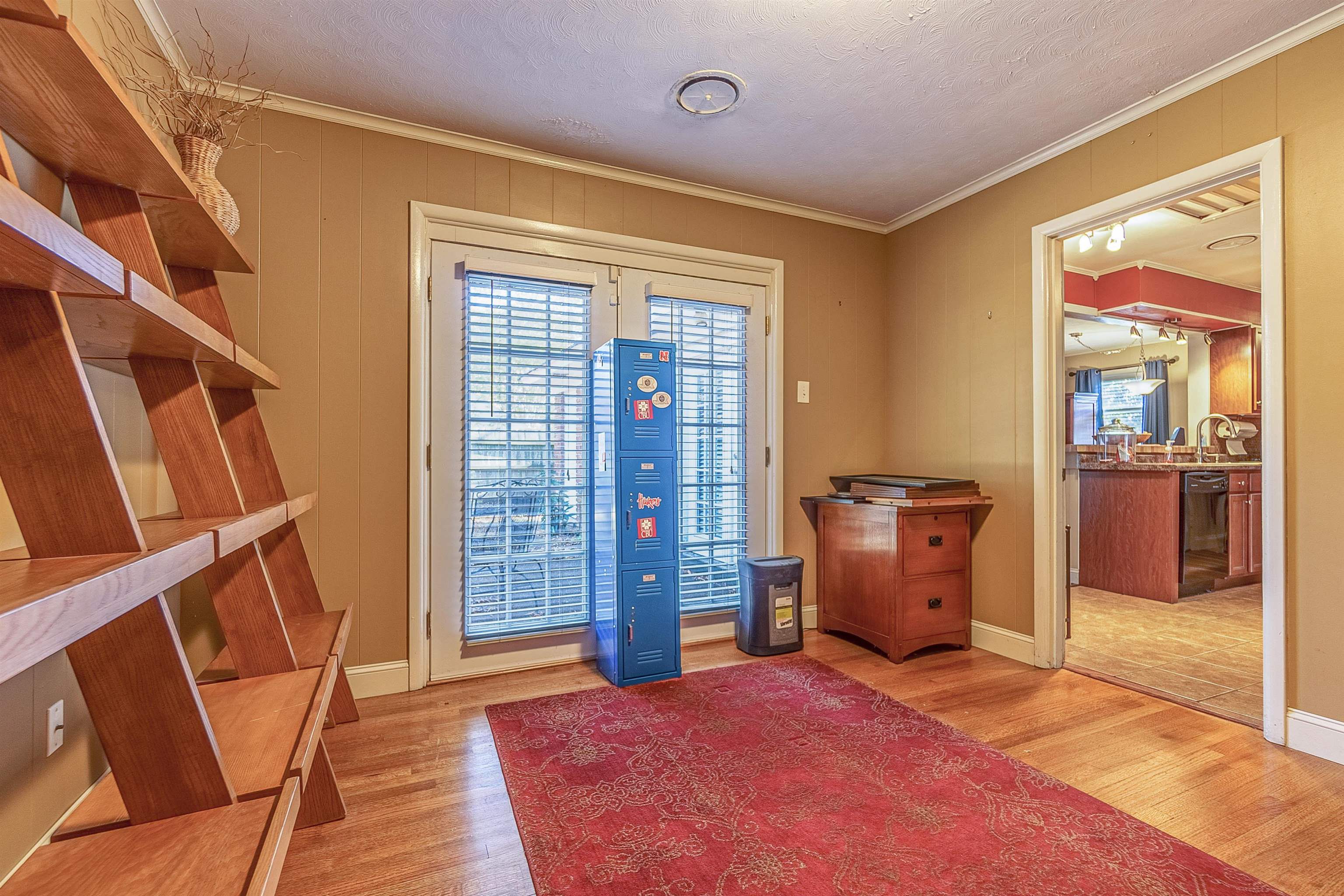 Doorway featuring a textured ceiling, light wood-type flooring, and crown molding