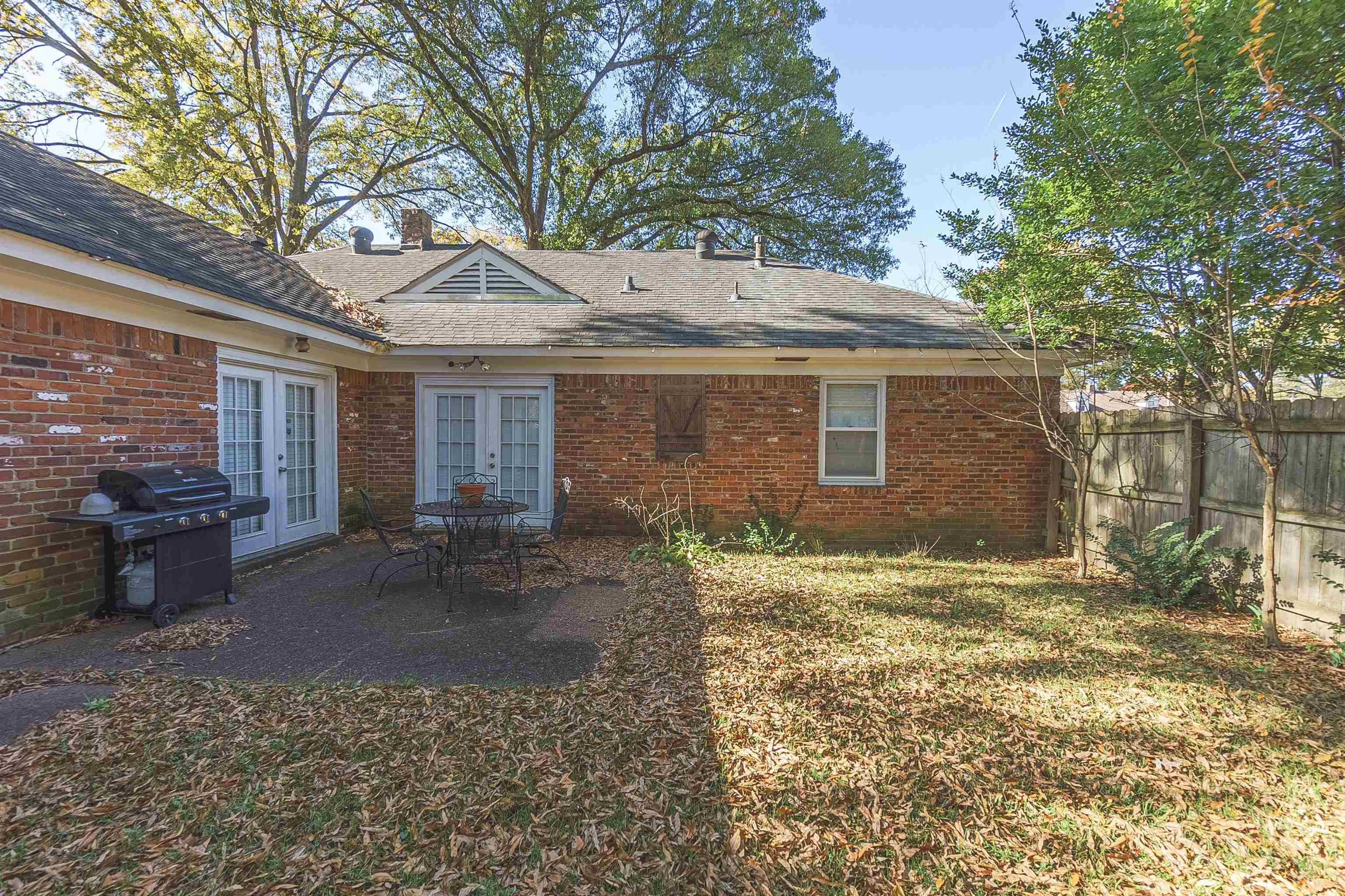 Back of house featuring a lawn, a patio, and french doors