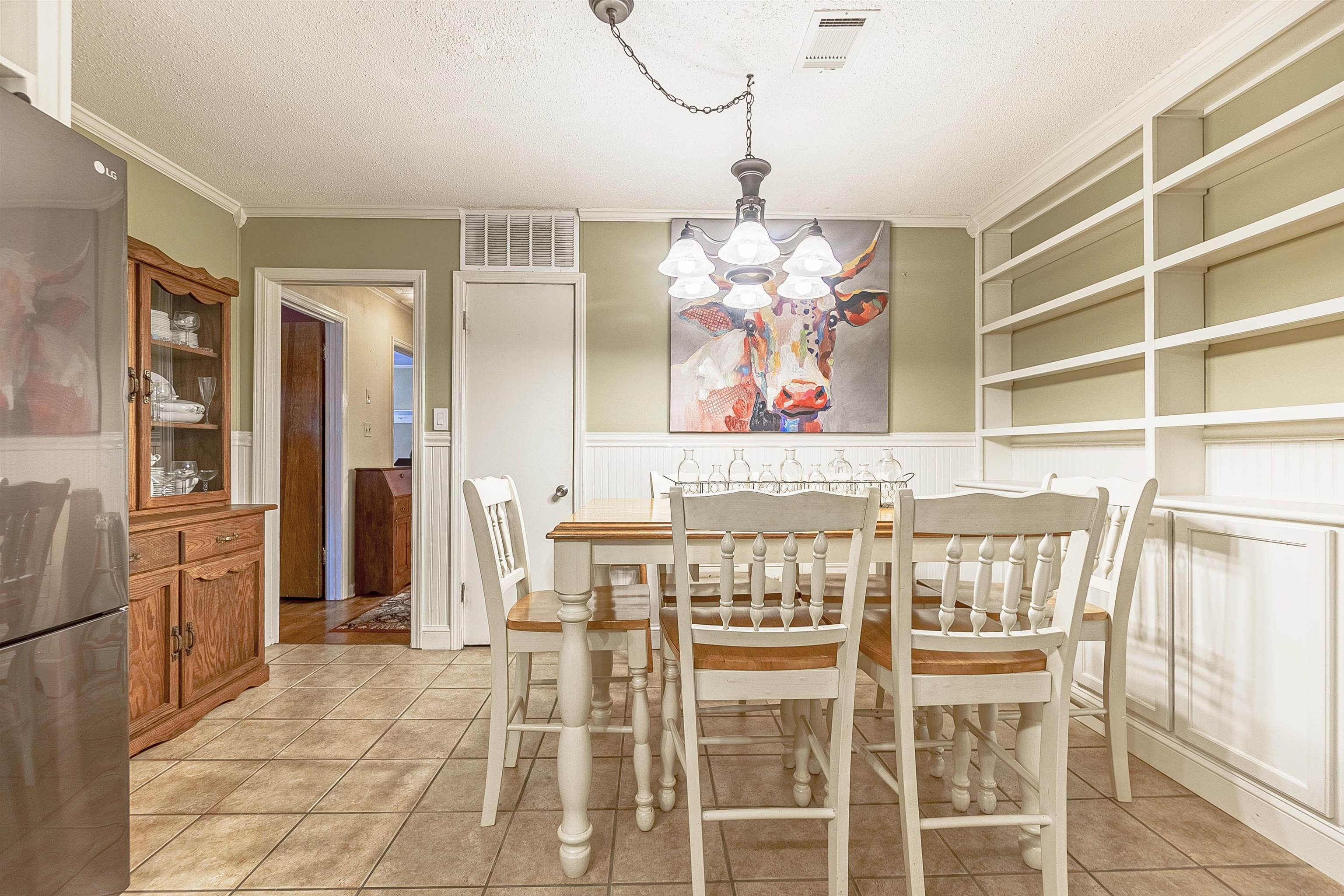 Tiled dining space featuring a textured ceiling, an inviting chandelier, and ornamental molding