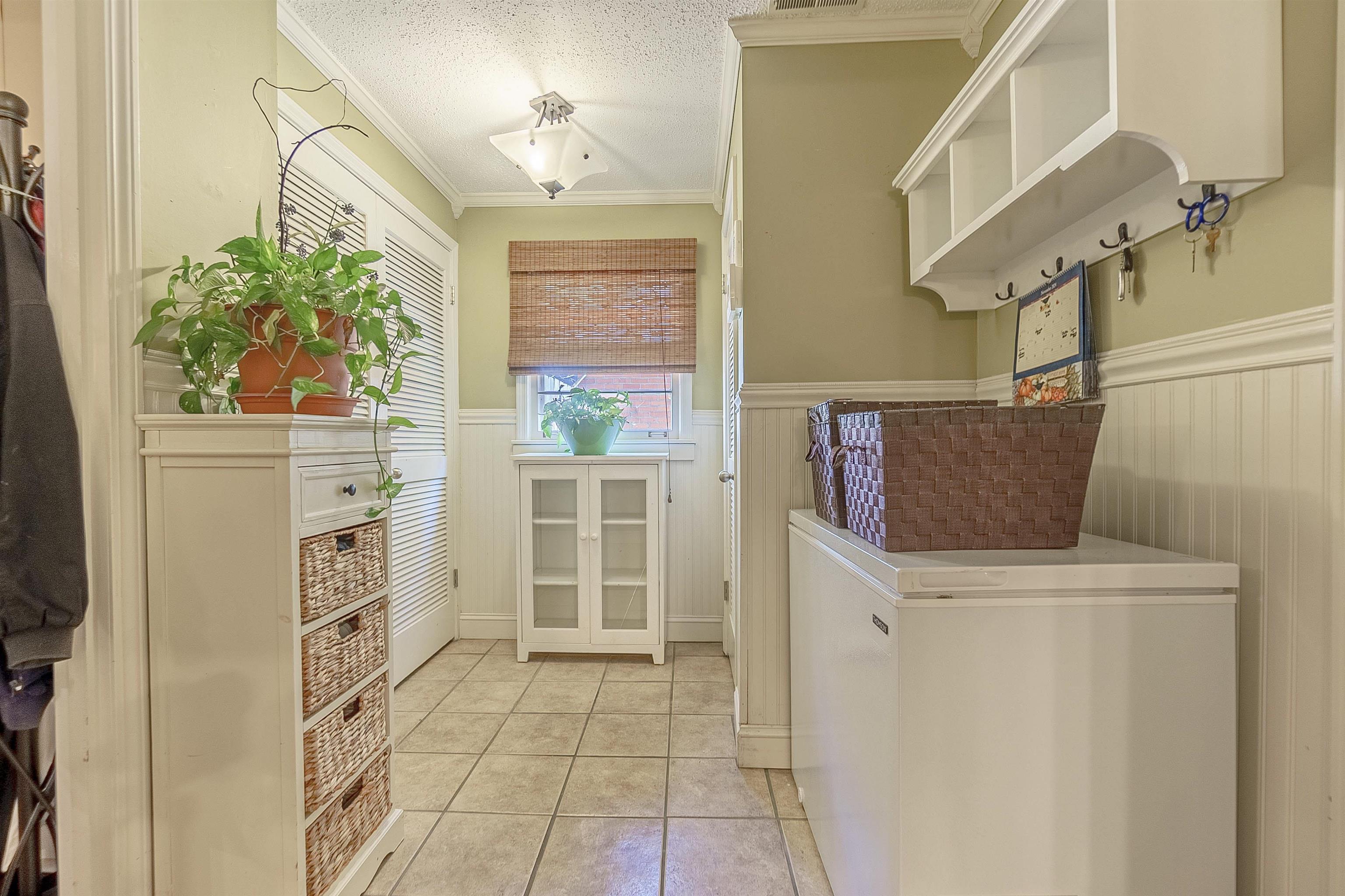 Interior space featuring crown molding, light tile patterned floors, and a textured ceiling
