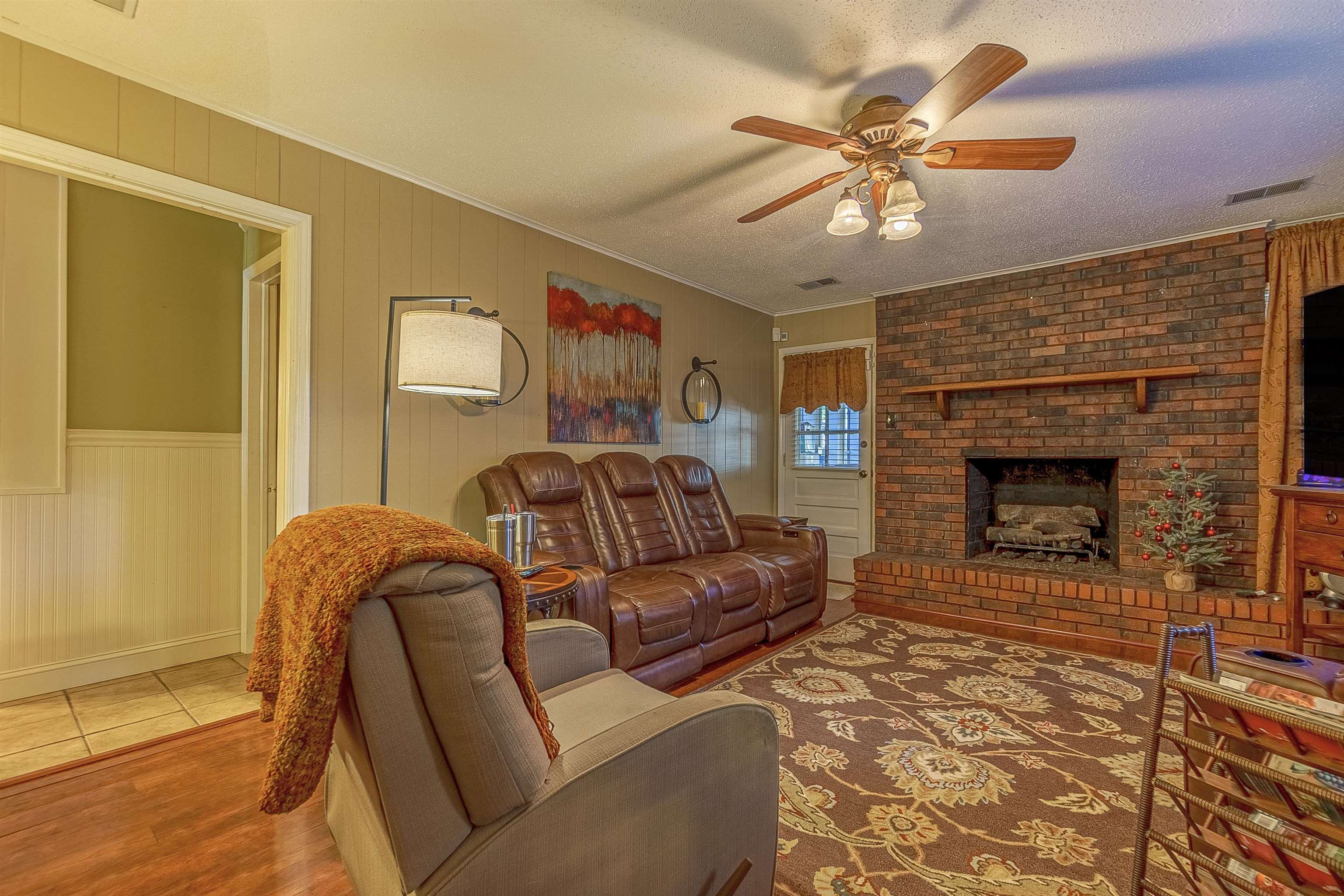 Living room with a fireplace, a textured ceiling, hardwood / wood-style flooring, and ceiling fan