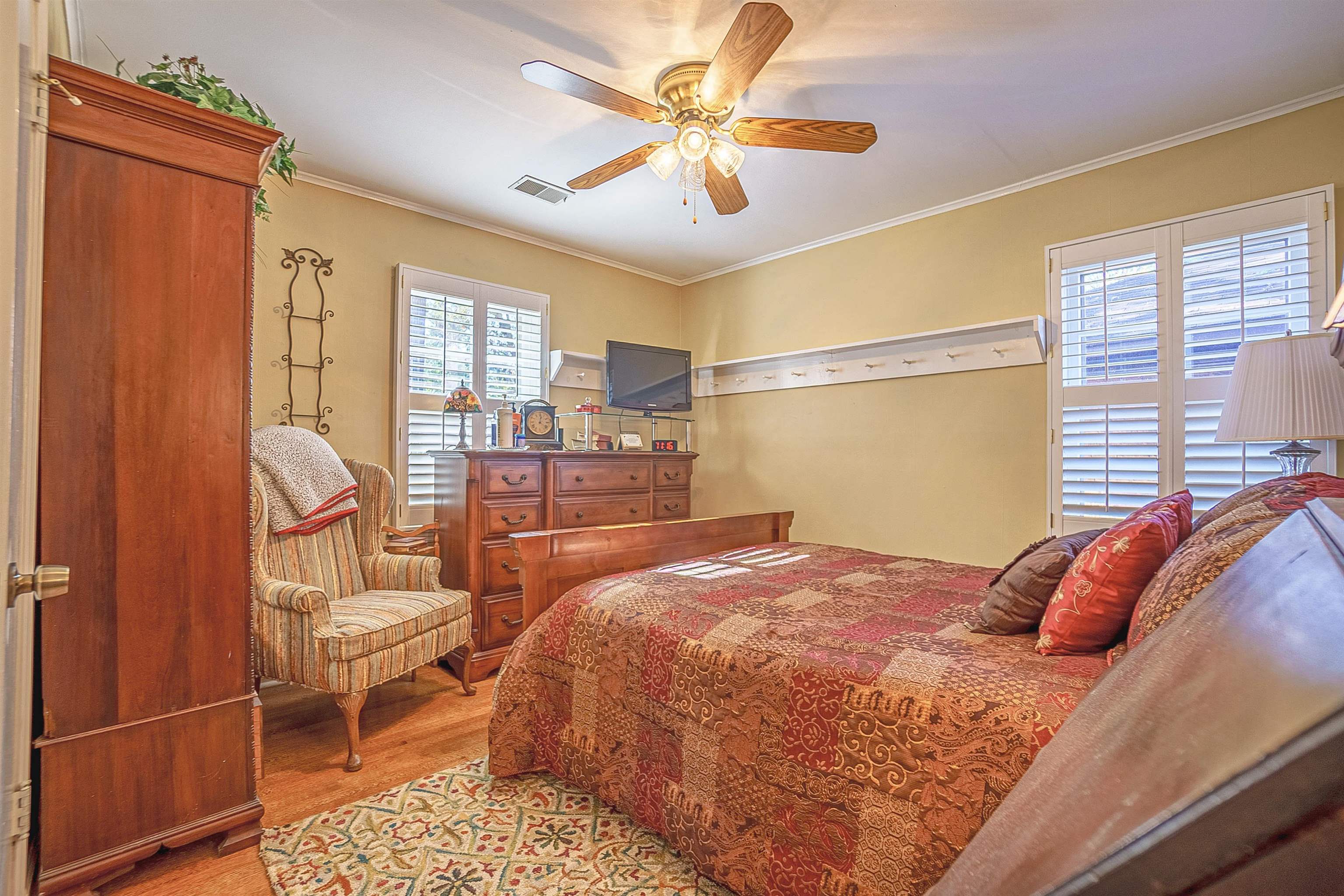 Bedroom featuring ceiling fan, light hardwood / wood-style flooring, and crown molding