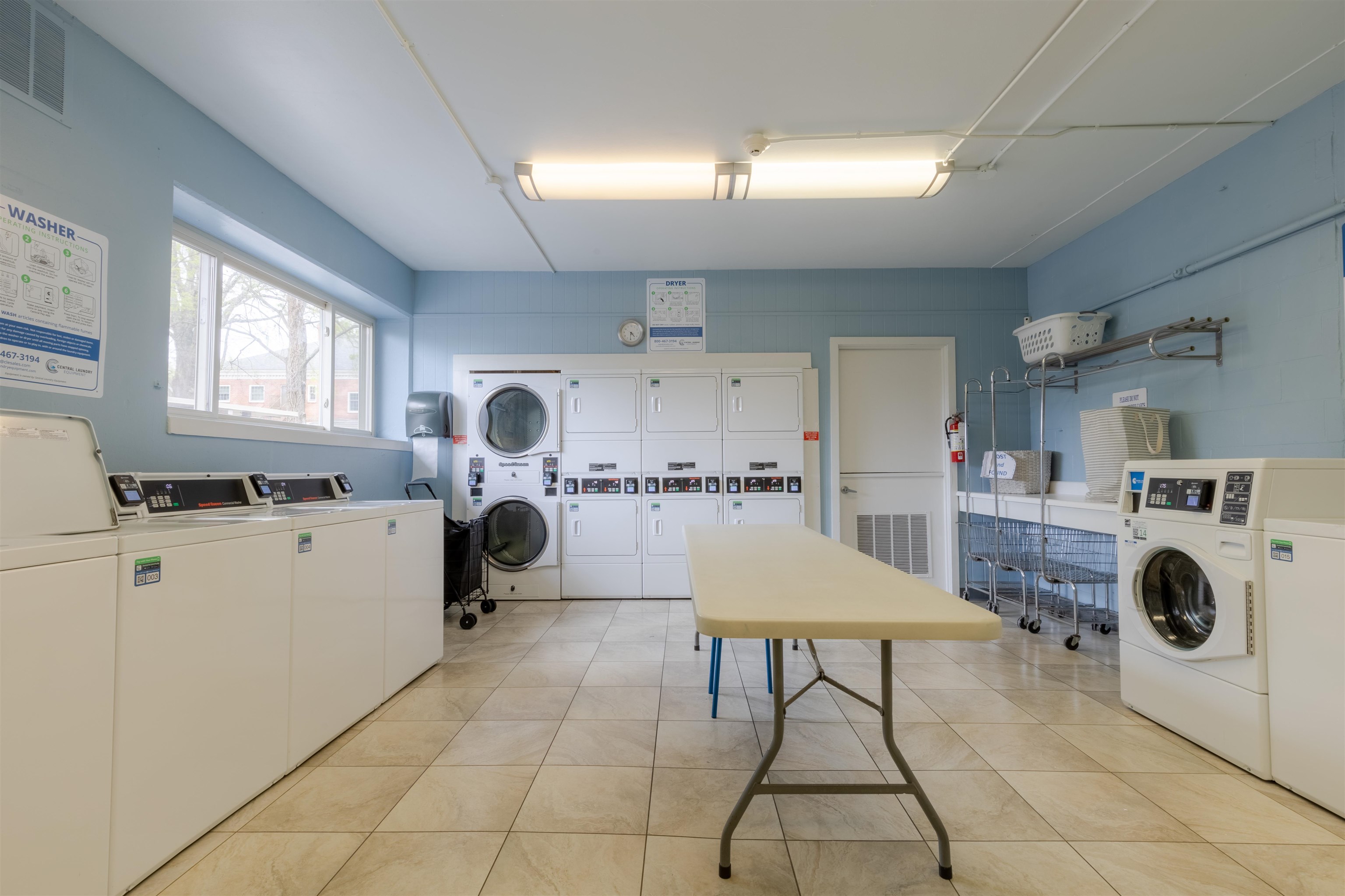 Laundry area with washing machine and dryer, light tile patterned floors, and stacked washer / dryer