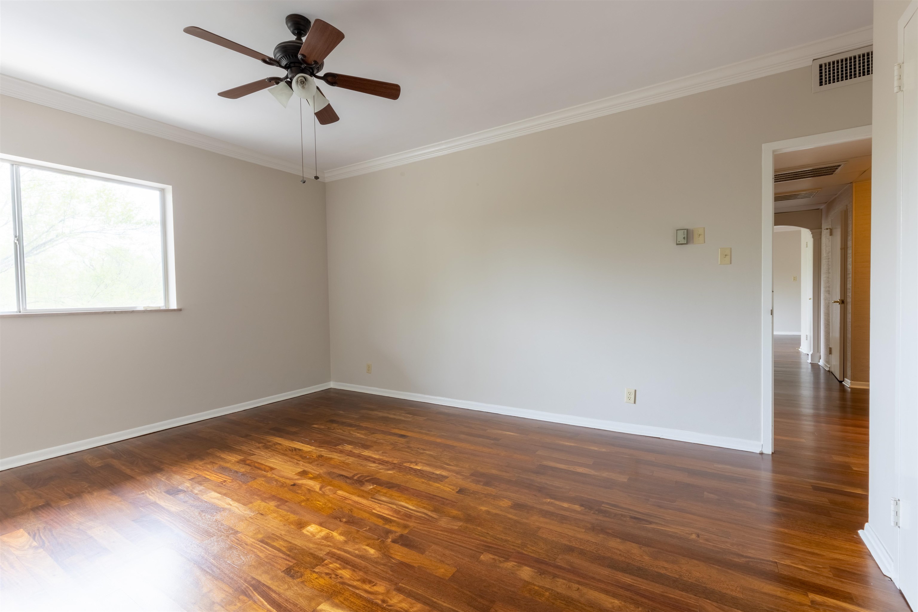 Unfurnished room featuring dark wood-type flooring, ceiling fan, and ornamental molding