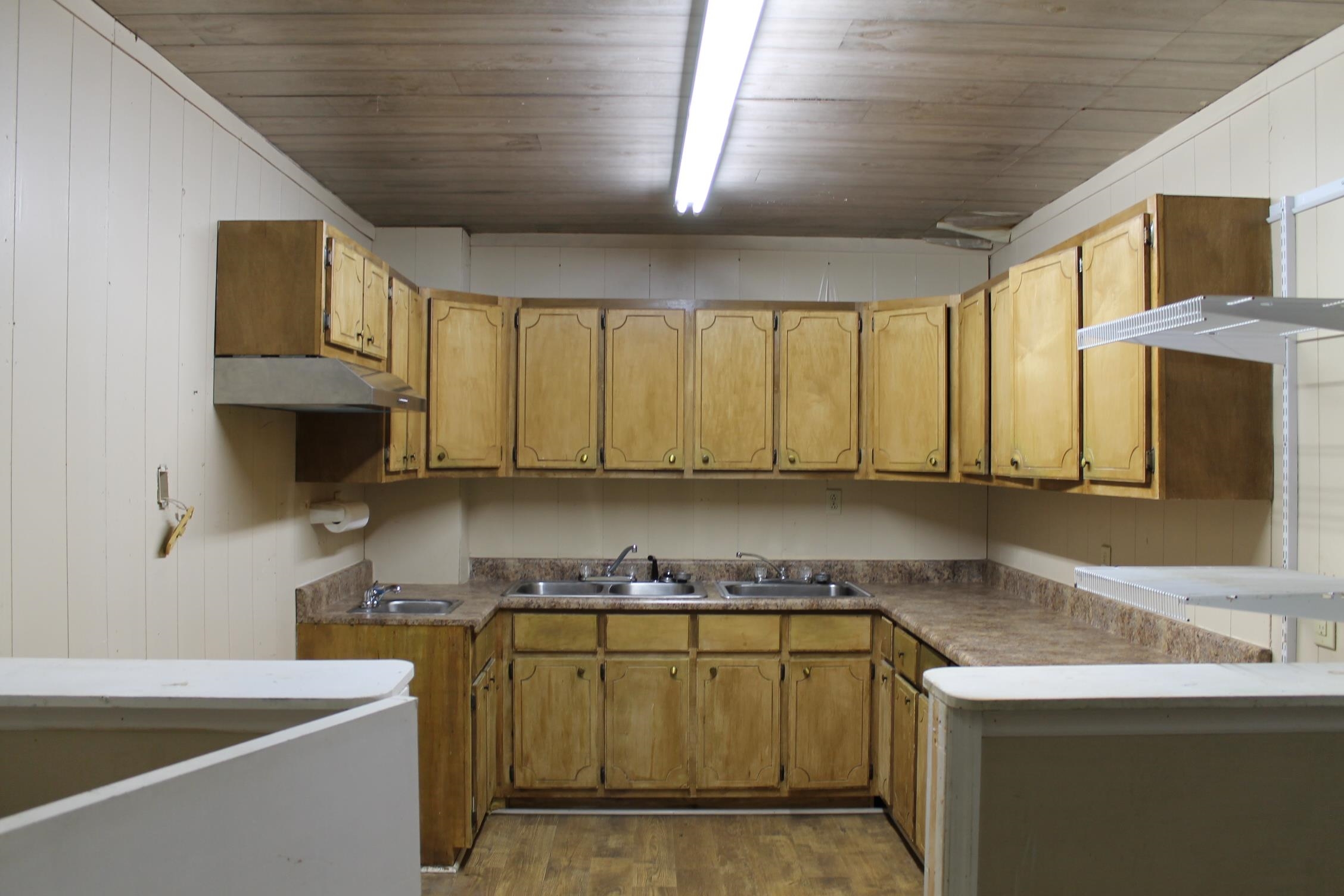 Kitchen with sink, dark wood-type flooring, and wooden walls