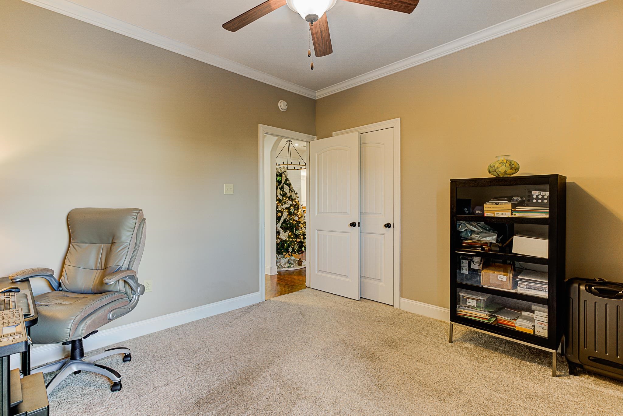 Office with ceiling fan, light colored carpet, and ornamental molding