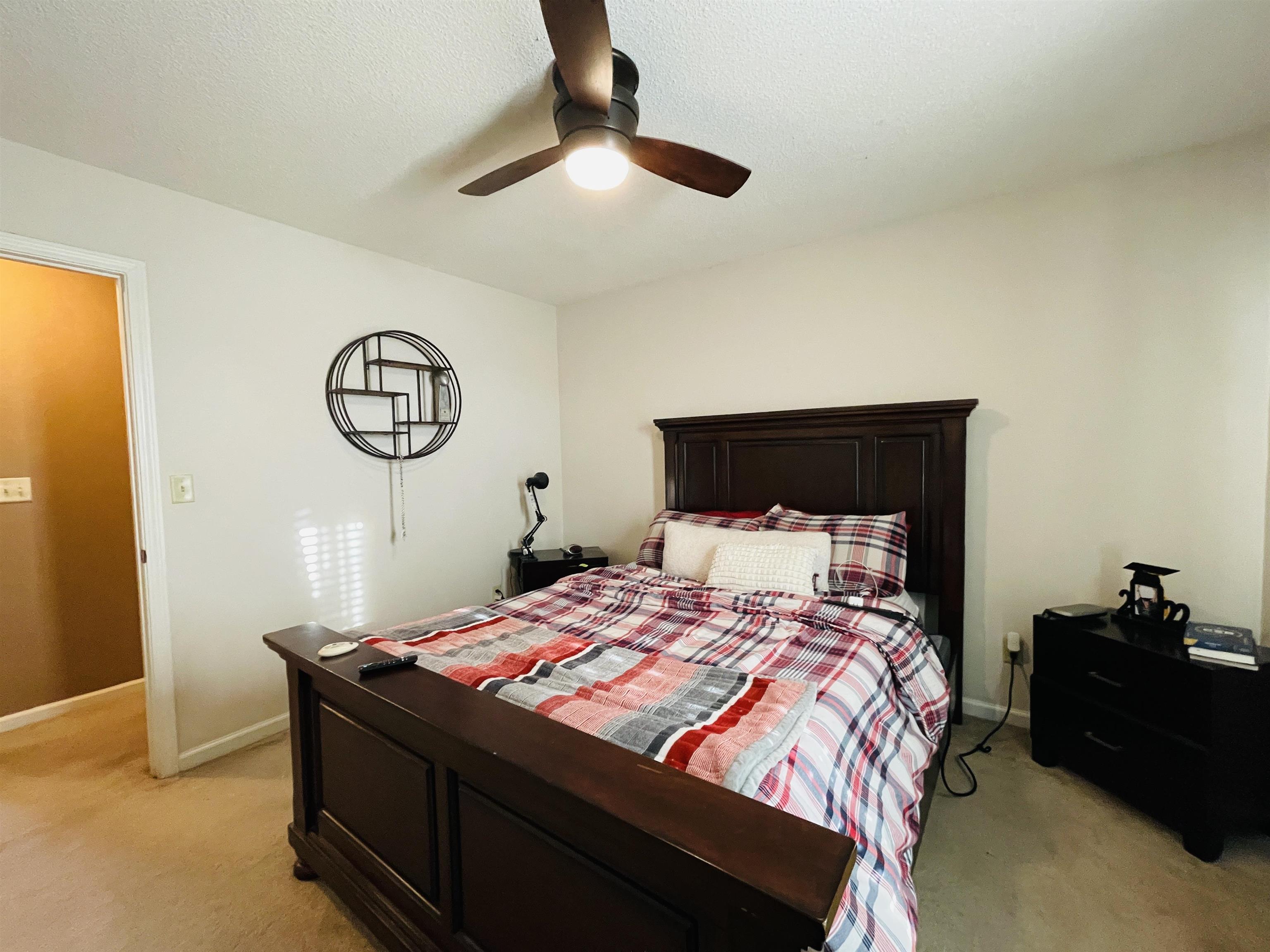 Carpeted bedroom featuring ceiling fan and a textured ceiling