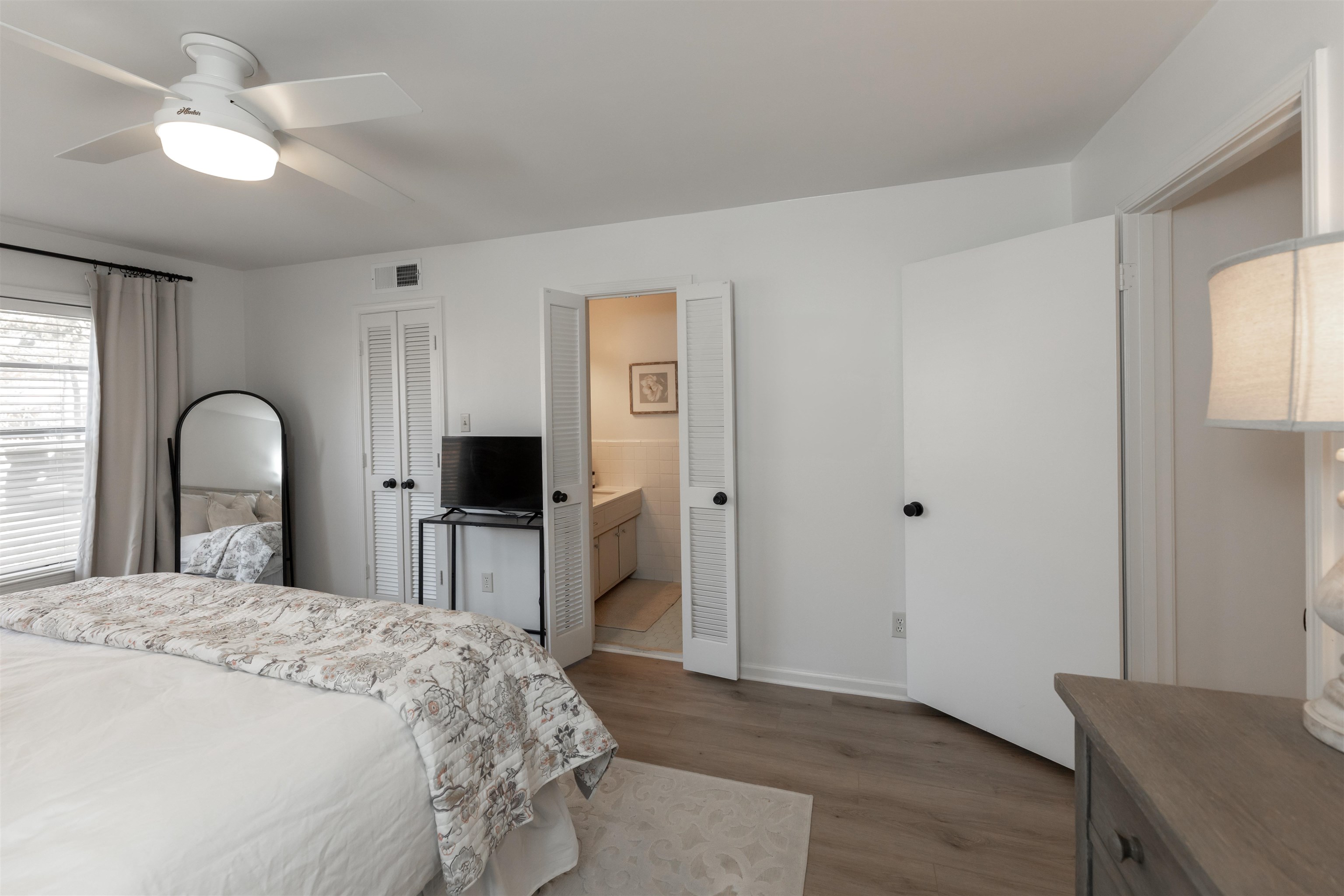 Bedroom featuring hardwood / wood-style flooring, ceiling fan, and ensuite bath