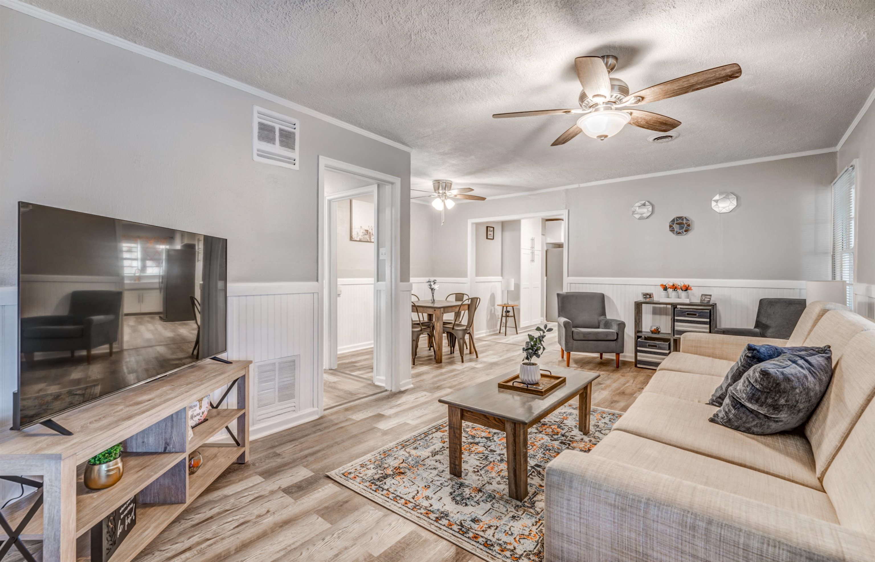 Living room featuring ceiling fan, light hardwood / wood-style floors, ornamental molding, and a textured ceiling