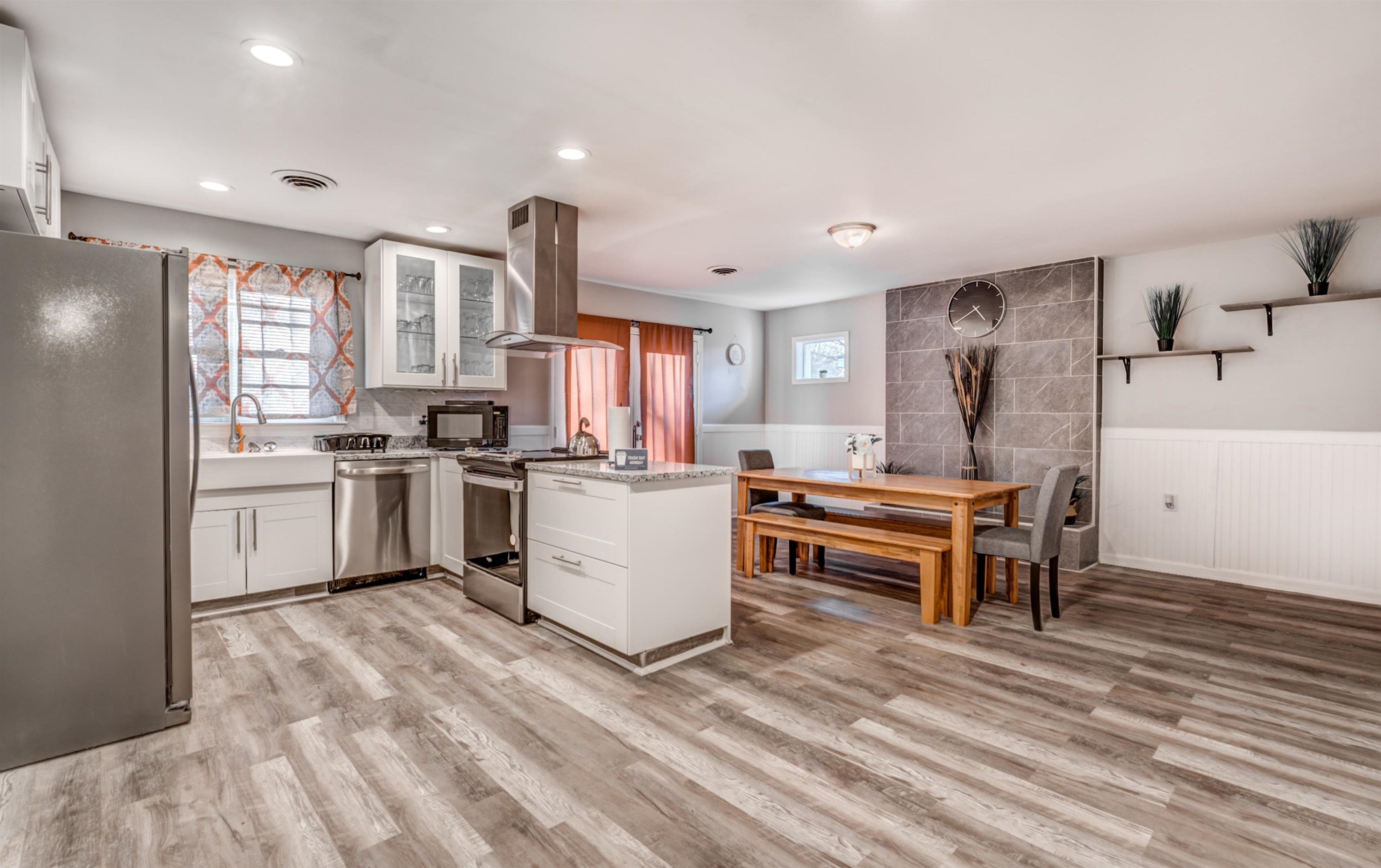 Kitchen with white cabinets, appliances with stainless steel finishes, island range hood, and light hardwood / wood-style floors
