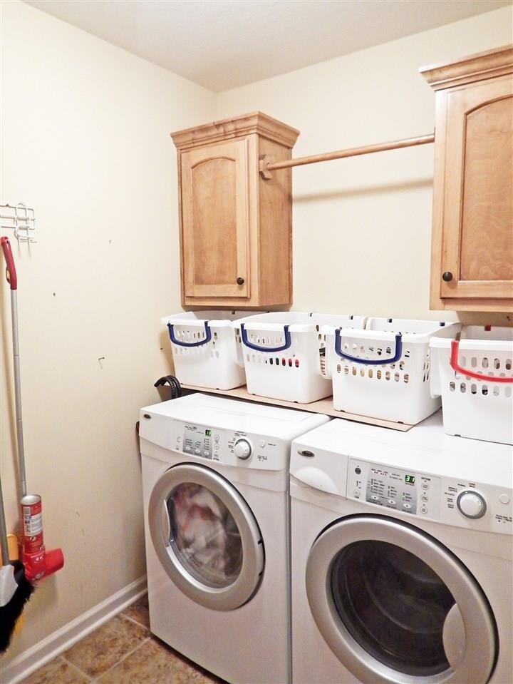 Laundry room with dark tile patterned flooring, cabinets, and separate washer and dryer