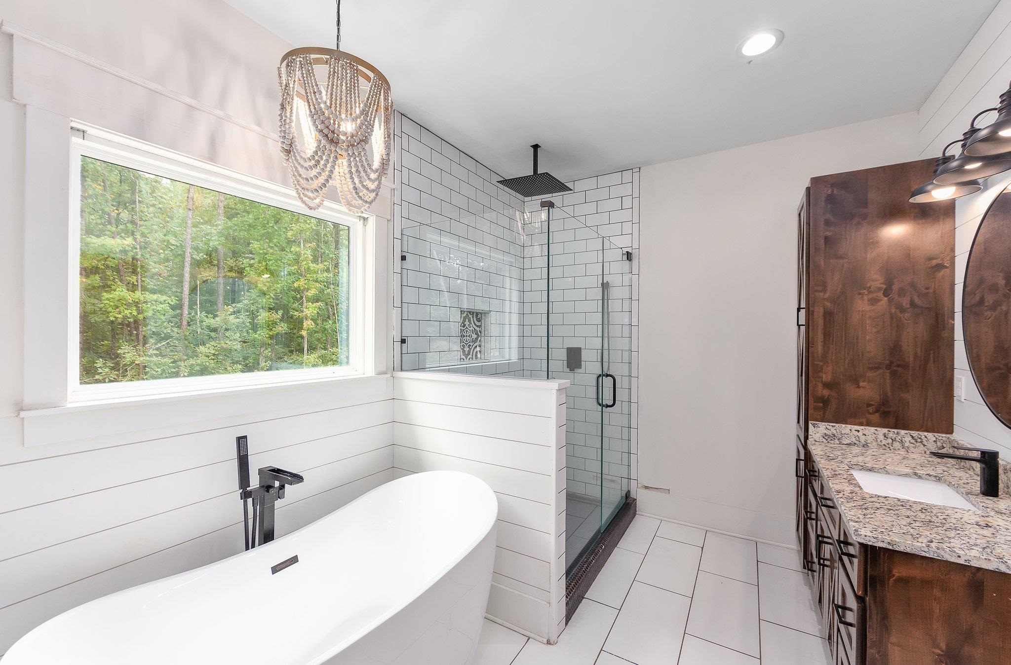 Bathroom featuring vanity, wood walls, plus walk in shower, tile patterned flooring, and a chandelier