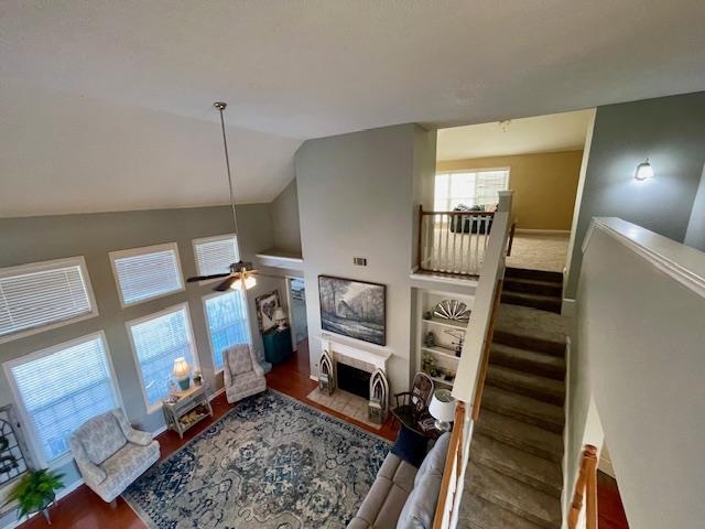 Living room with ceiling fan, wood-type flooring, and lofted ceiling