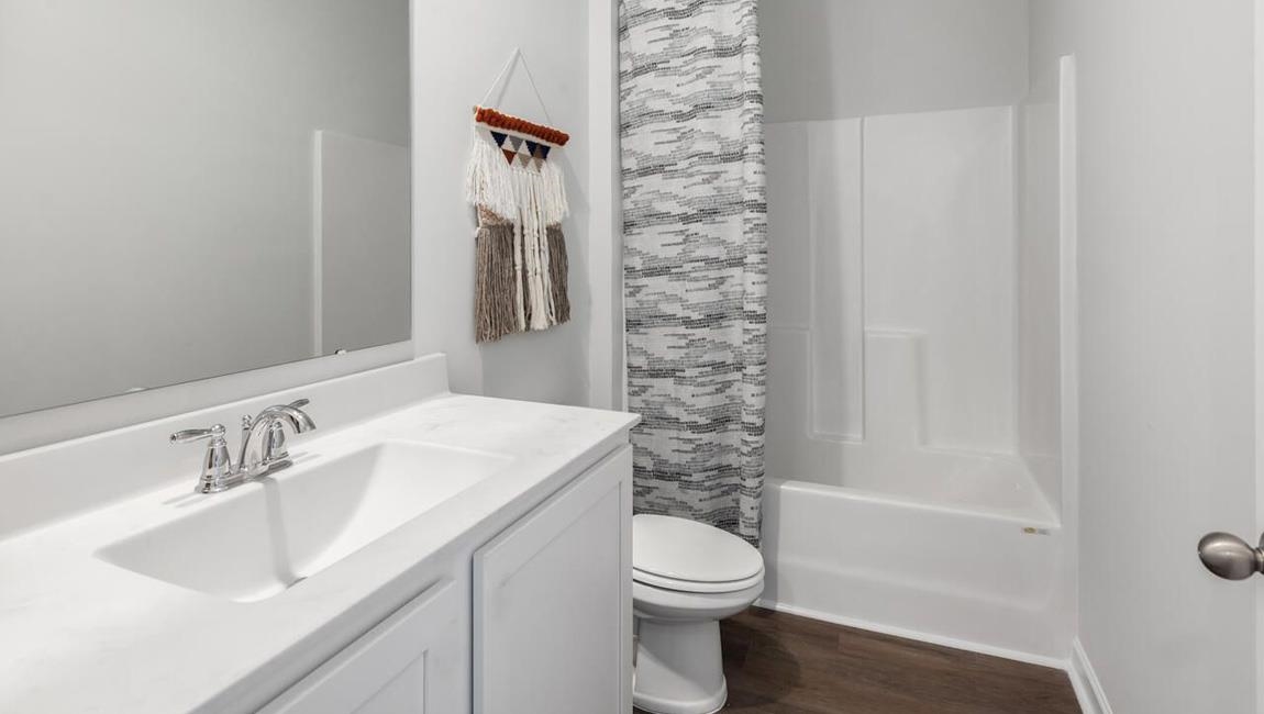 Full bathroom with vanity, shower / tub combo, wood-type flooring, and toilet