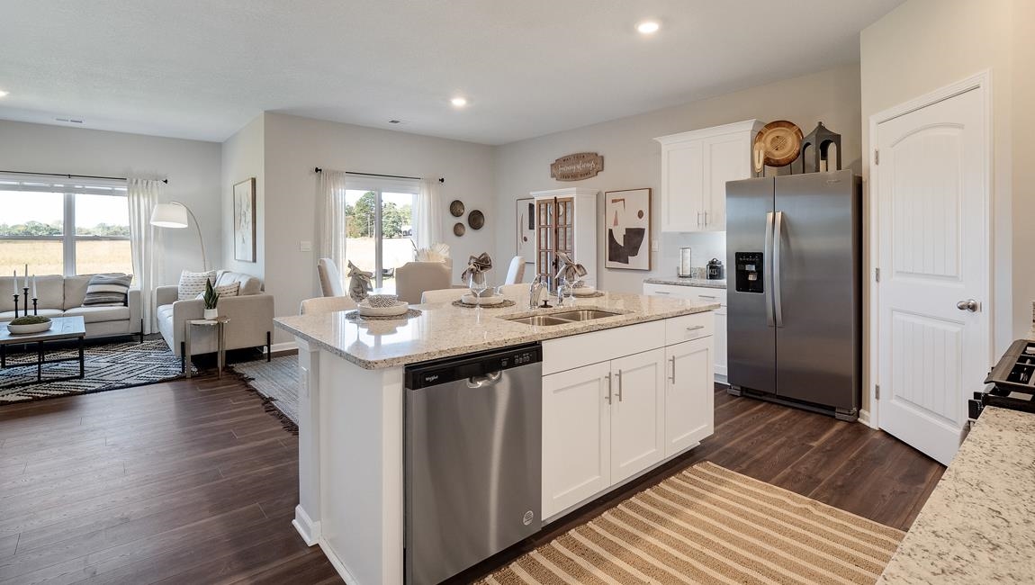 Kitchen featuring appliances with stainless steel finishes, white cabinets, sink, an island with sink, and dark wood-type flooring