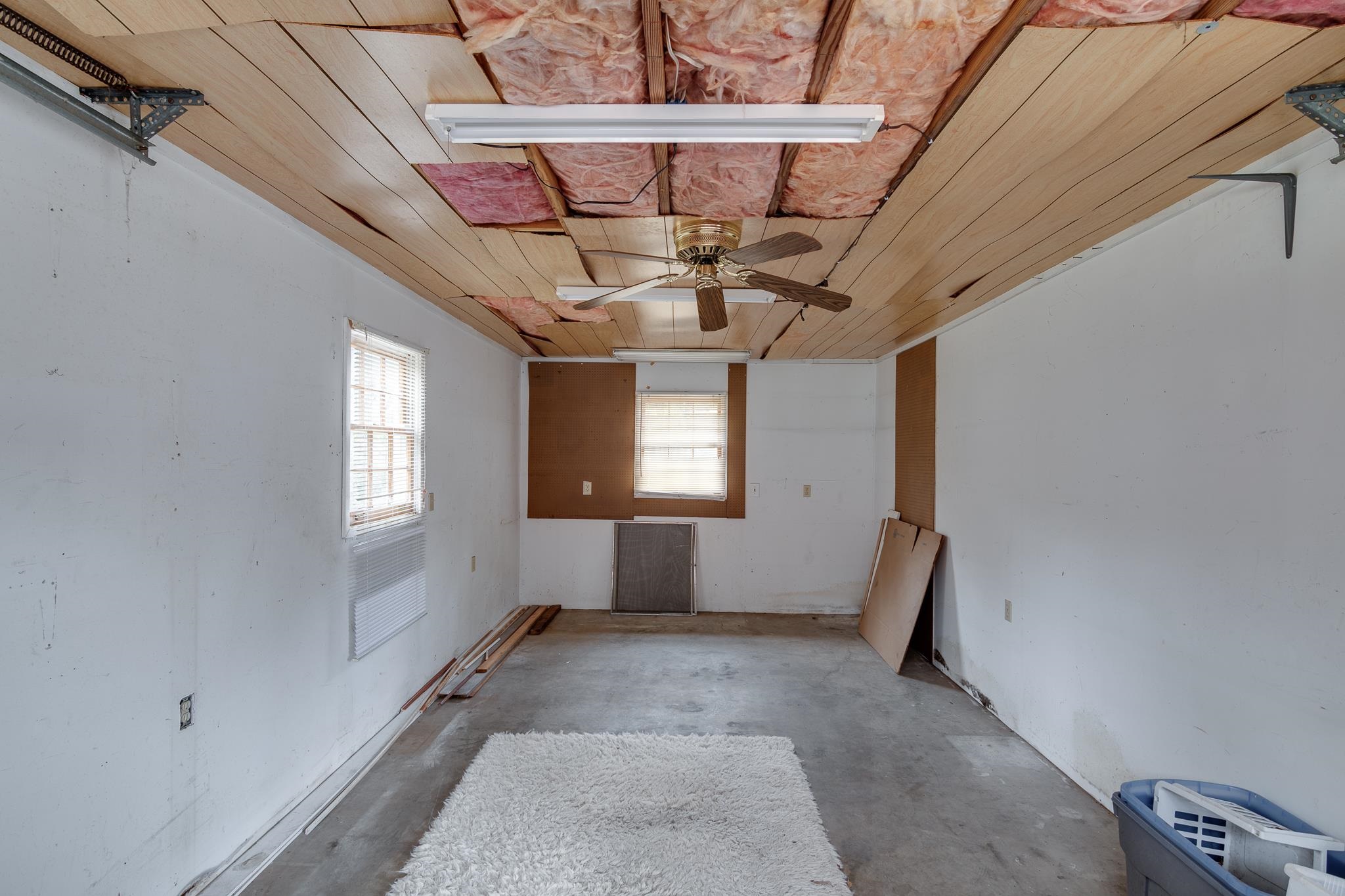 Spare room with wood ceiling, a wealth of natural light, ceiling fan, and concrete flooring