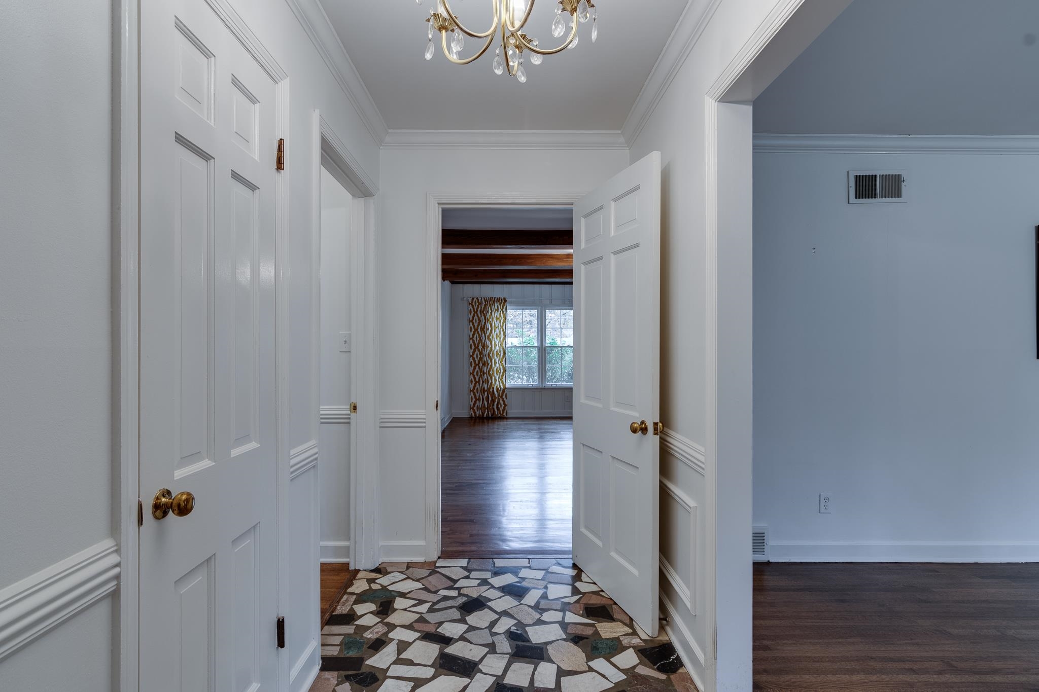 Corridor featuring dark hardwood / wood-style flooring, ornamental molding, and an inviting chandelier