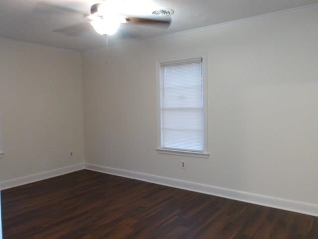 Empty room featuring crown molding, ceiling fan, and dark wood-type flooring