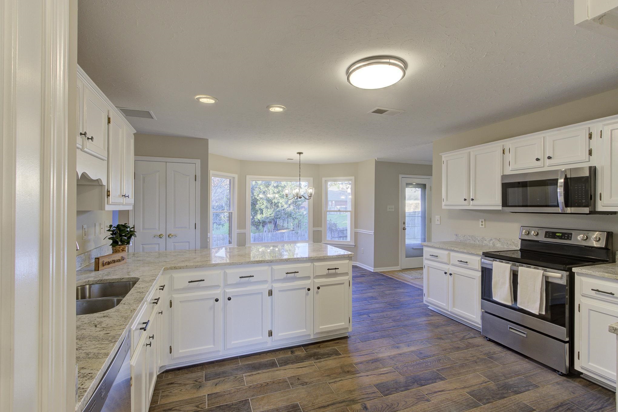 Kitchen with white cabinetry, hanging light fixtures, dark hardwood / wood-style floors, a chandelier, and appliances with stainless steel finishes