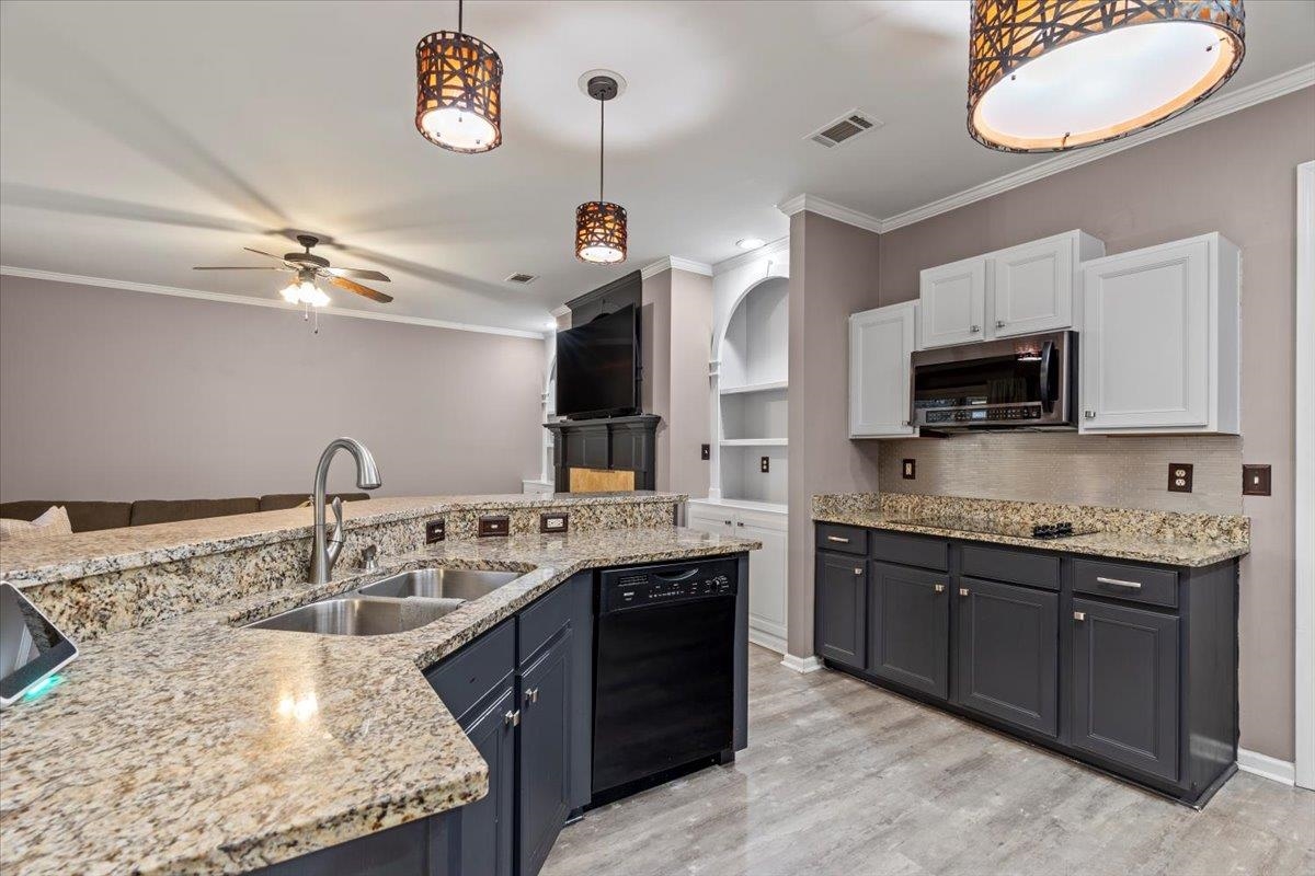 Kitchen with white cabinets, sink, hanging light fixtures, ceiling fan, and black dishwasher