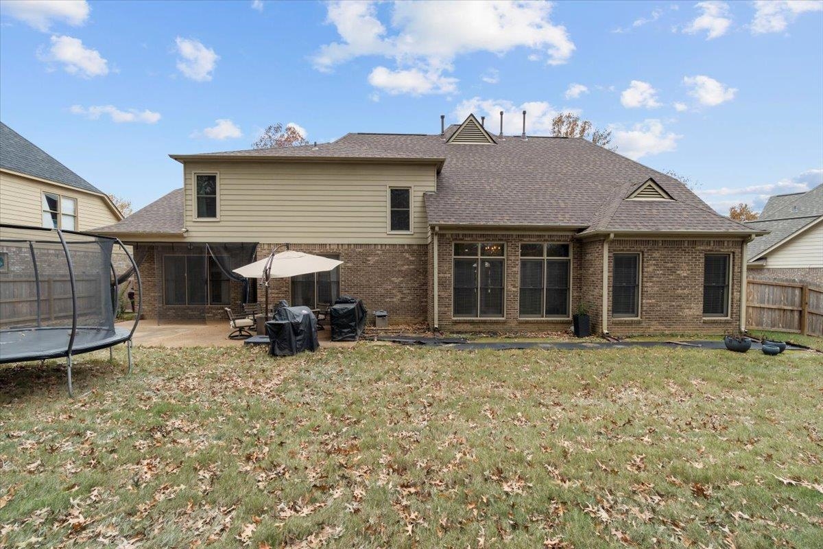 Back of house with a yard, a patio, and a trampoline