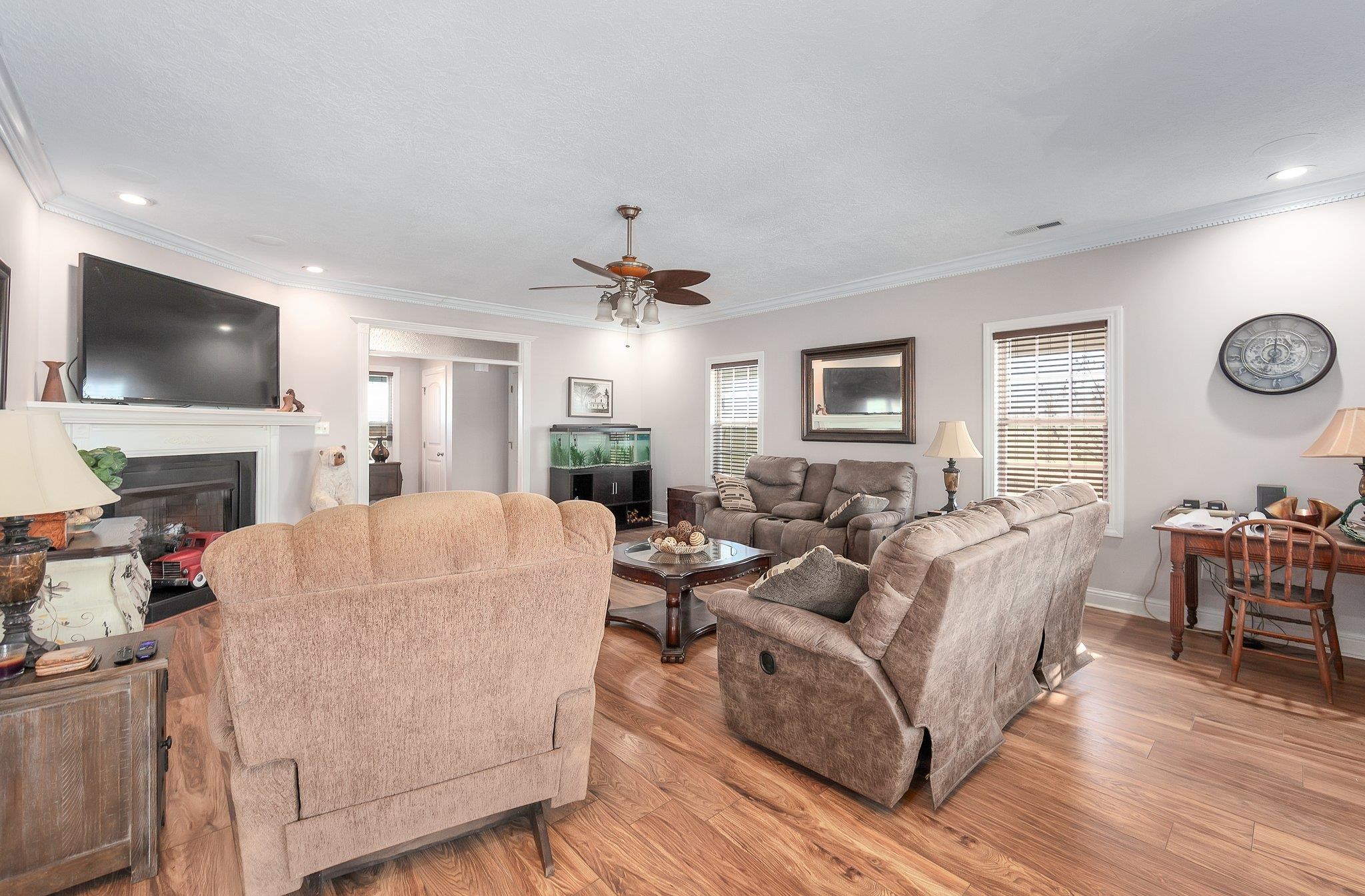 Living room featuring ceiling fan, light wood-type flooring, and ornamental molding