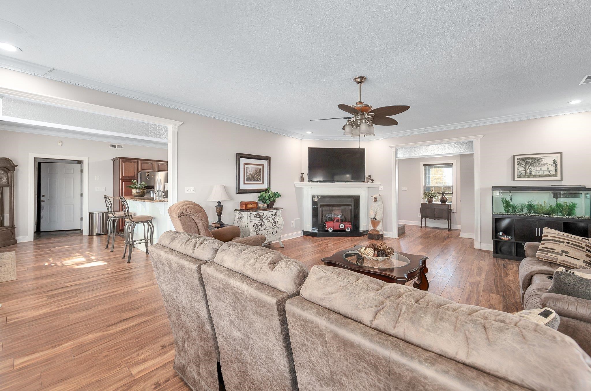 Living room with ceiling fan, hardwood / wood-style floors, crown molding, and a textured ceiling