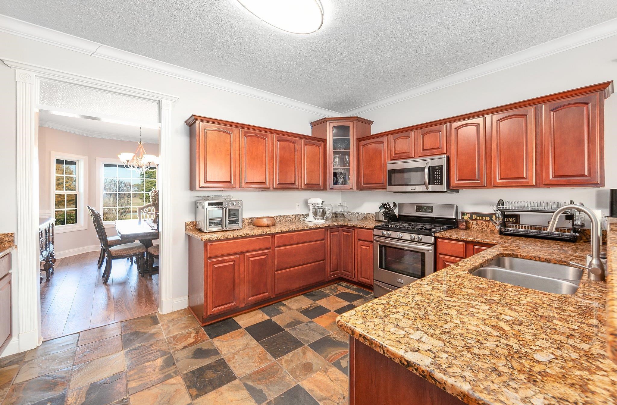 Kitchen featuring a textured ceiling, stainless steel appliances, an inviting chandelier, and sink