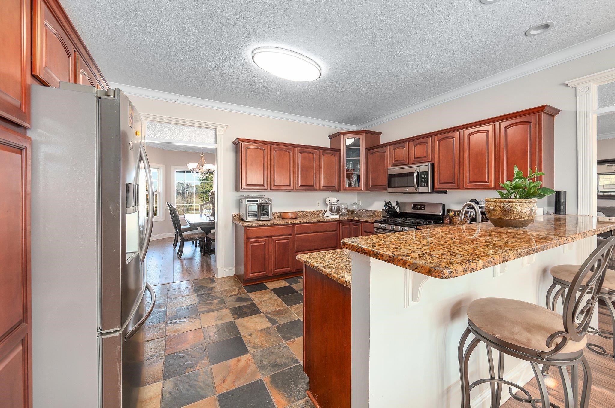 Kitchen with an inviting chandelier, ornamental molding, a textured ceiling, and appliances with stainless steel finishes