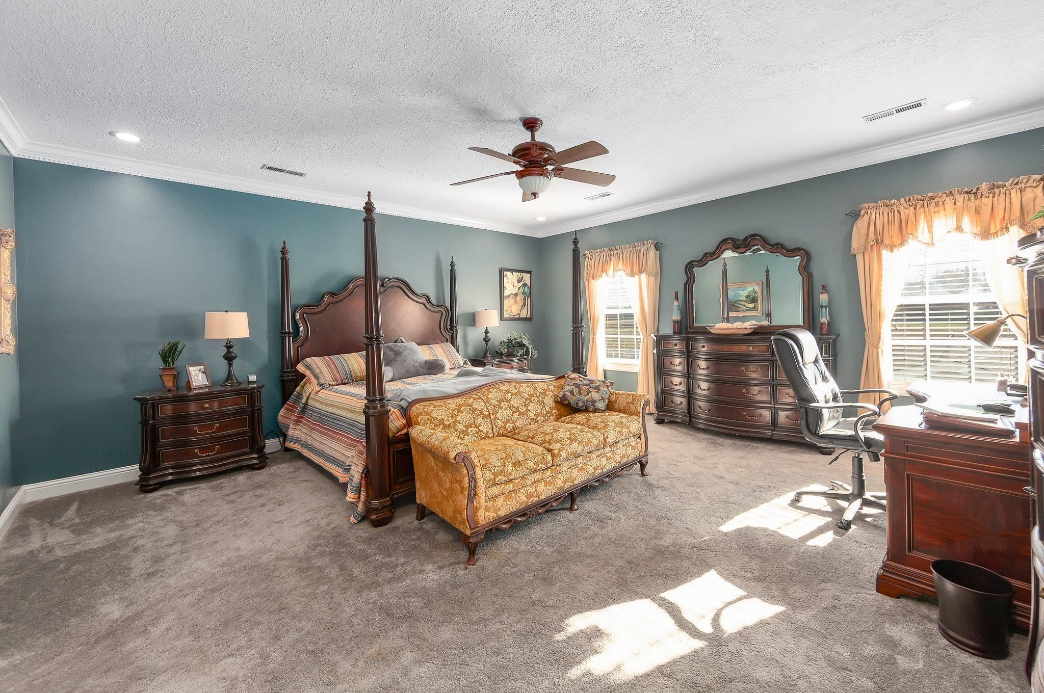 Carpeted bedroom featuring a textured ceiling, ceiling fan, and crown molding