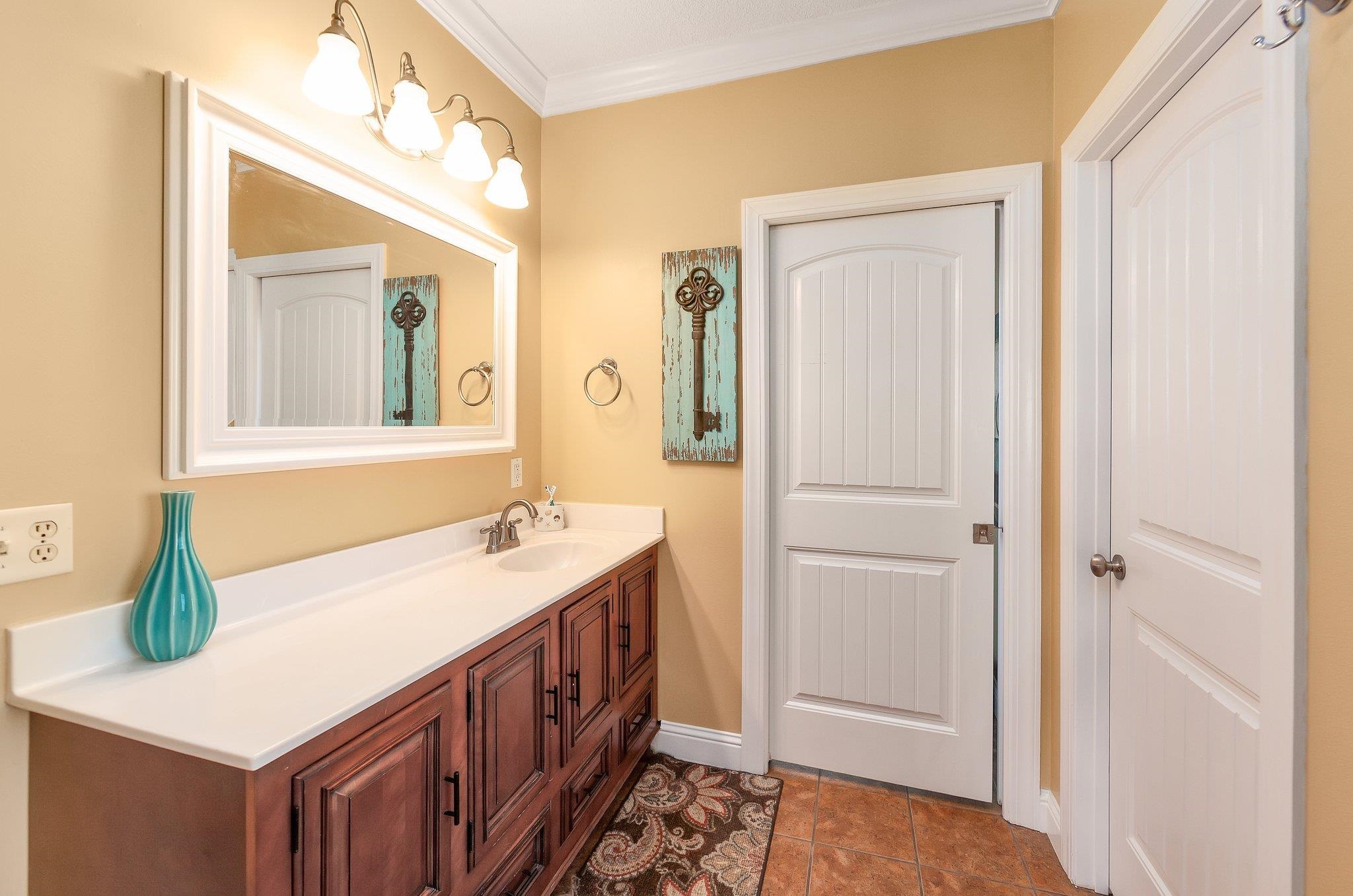 Bathroom featuring tile patterned flooring, vanity, and crown molding