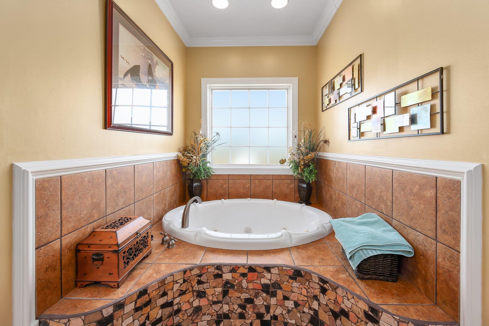 Bathroom with ornamental molding and tiled tub