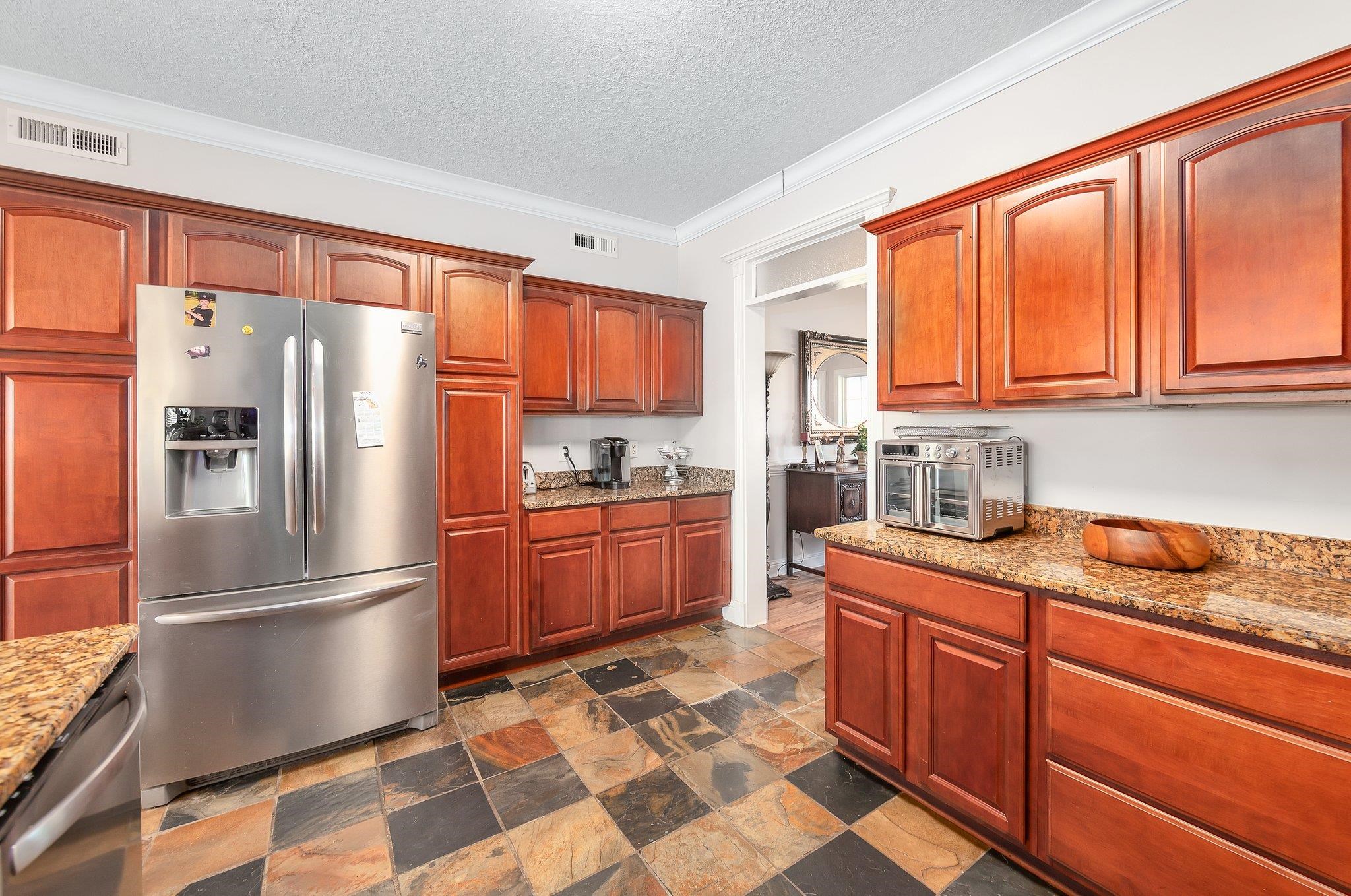 Kitchen featuring a textured ceiling, stainless steel appliances, light stone counters, and ornamental molding