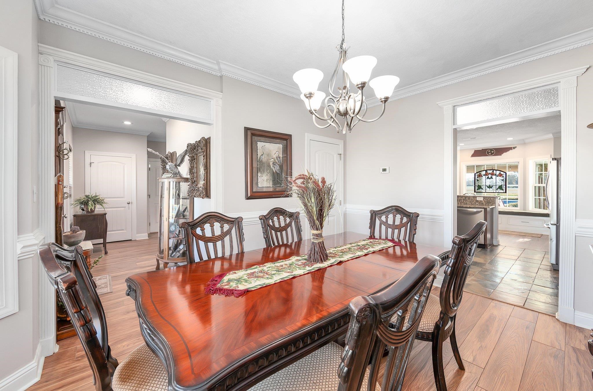 Dining space with light wood-type flooring, crown molding, and a chandelier